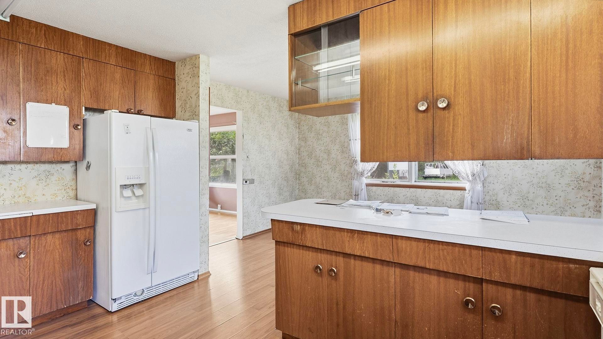 Wood-finish cabinetry with white countertops, wood-finish flooring, and a white side-by-side refrigerator - 52012 Hwy 21, Rural Strathcona County, AB - Indoor Photo Showing Kitchen