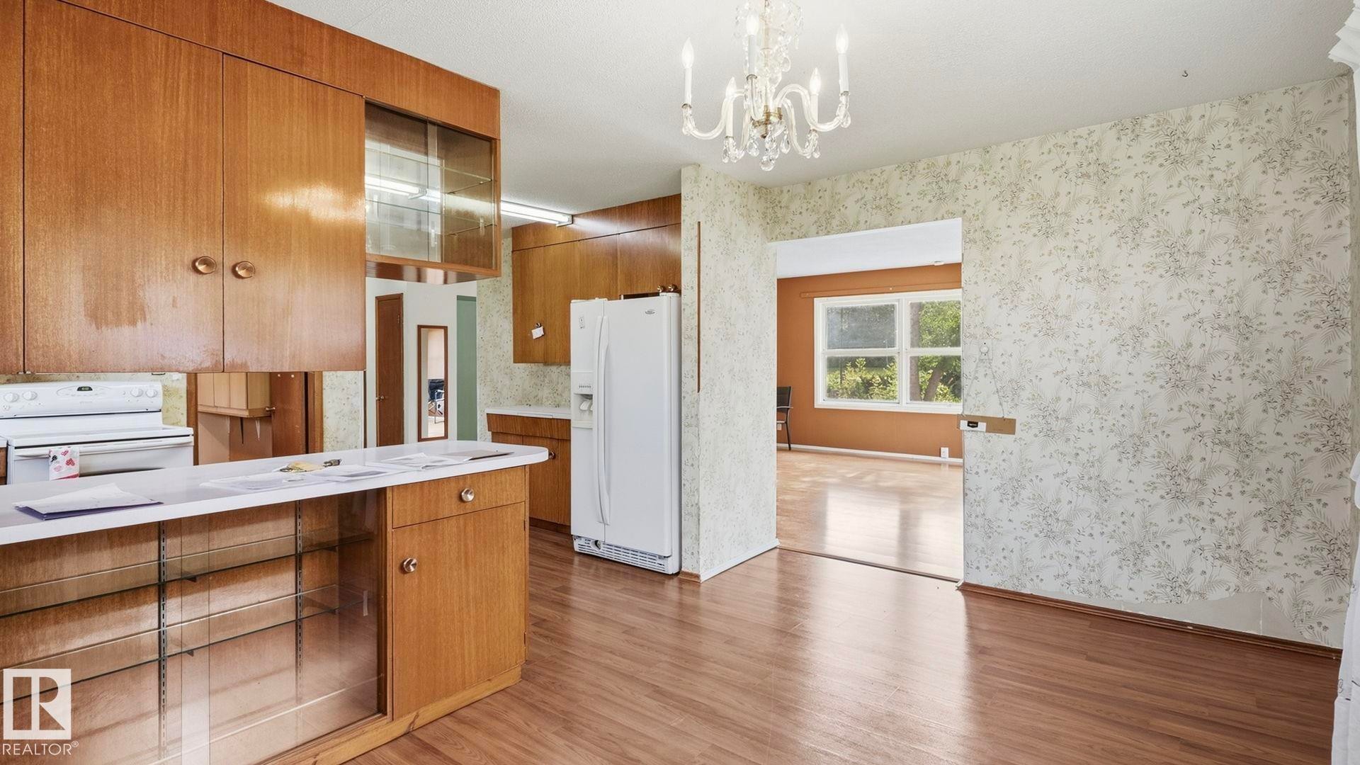 Kitchen featuring wood-finish cabinetry, white appliances, and a built-in breakfast bar with display shelving - 52012 Hwy 21, Rural Strathcona County, AB - Indoor Photo Showing Kitchen