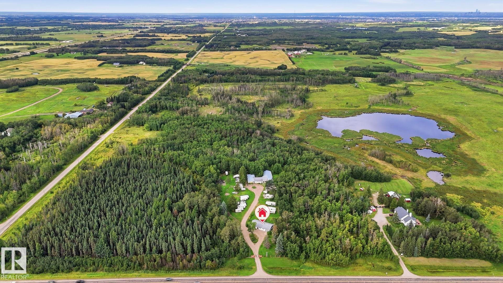Expansive property featuring dense wooded areas, open green fields, a substantial pond, and paved road frontage - 52012 Hwy 21, Rural Strathcona County, AB - Outdoor With View