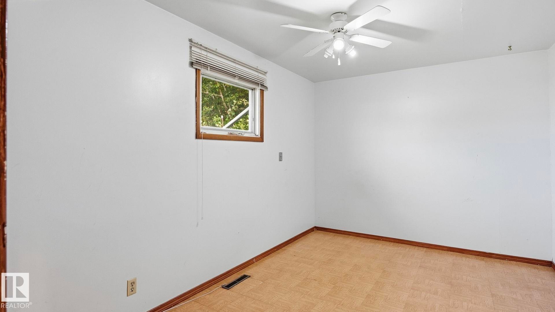 White walls, wood-finish flooring, and a ceiling fan with integrated lighting - 52012 Hwy 21, Rural Strathcona County, AB - Indoor Photo Showing Other Room