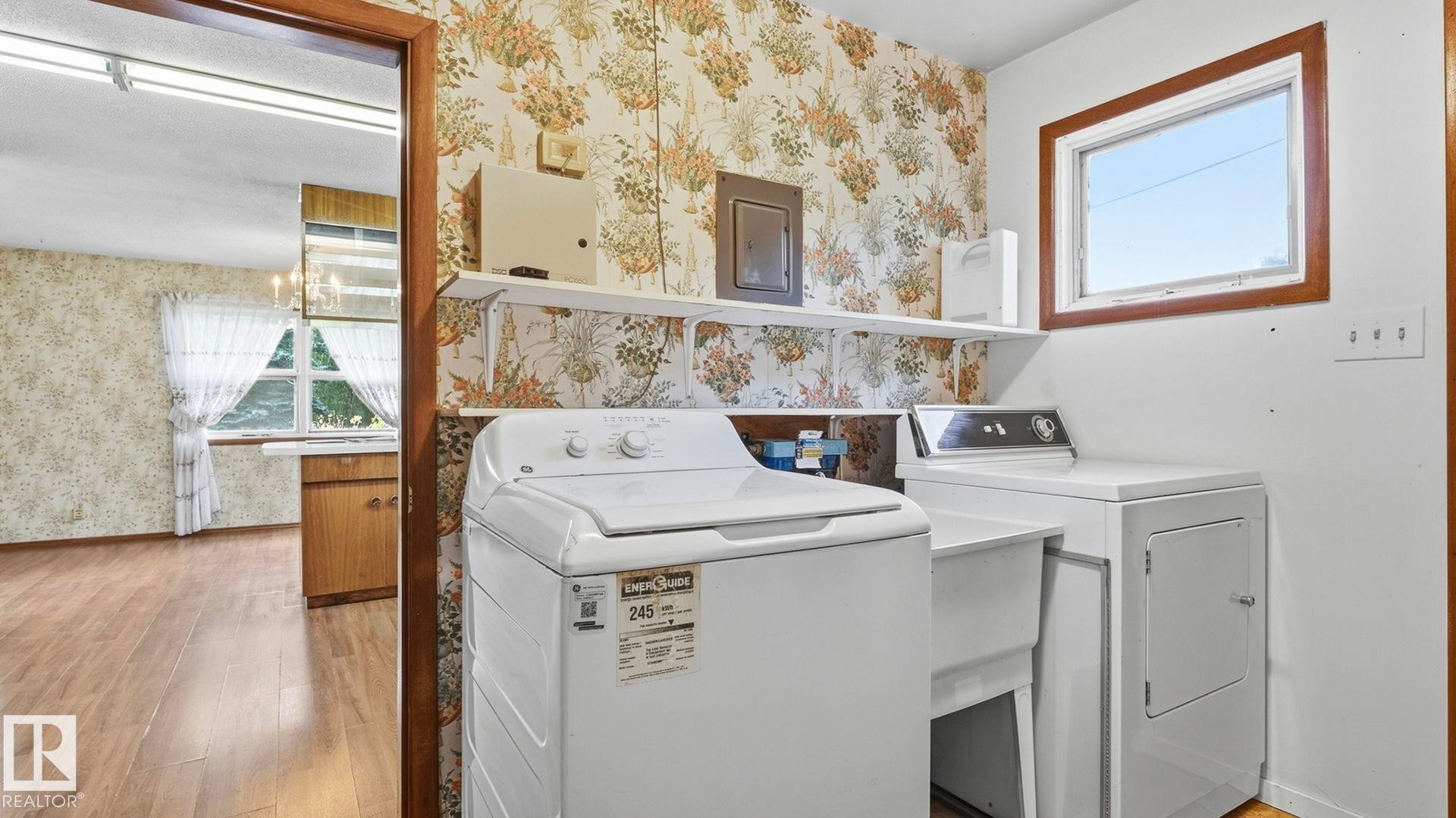Laundry area with a utility sink, wall-mounted shelving, and a framed window - 52012 Hwy 21, Rural Strathcona County, AB - Indoor Photo Showing Laundry Room