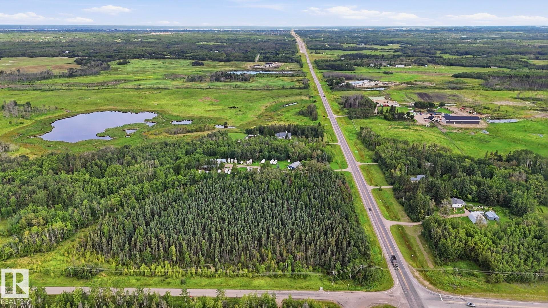 Expansive land featuring mature trees, open fields, and a natural pond - 52012 Hwy 21, Rural Strathcona County, AB - Outdoor With View
