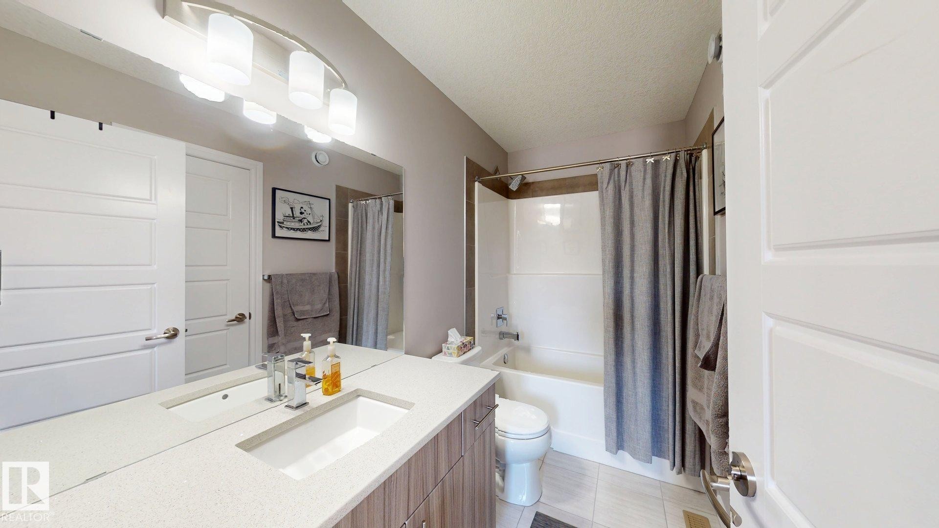 Modern vanity with an integrated sink, polished chrome faucet, and expansive mirror - 17359 49 Street Nw, Edmonton, AB - Indoor Photo Showing Bathroom