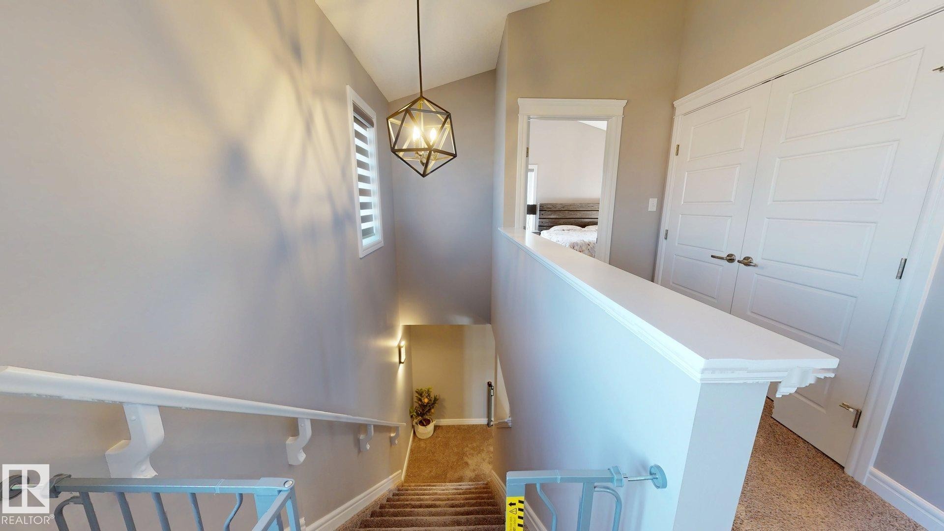 Staircase featuring a geometric pendant light, white paneled doors, and a partial window - 17359 49 Street Nw, Edmonton, AB - Indoor Photo Showing Other Room