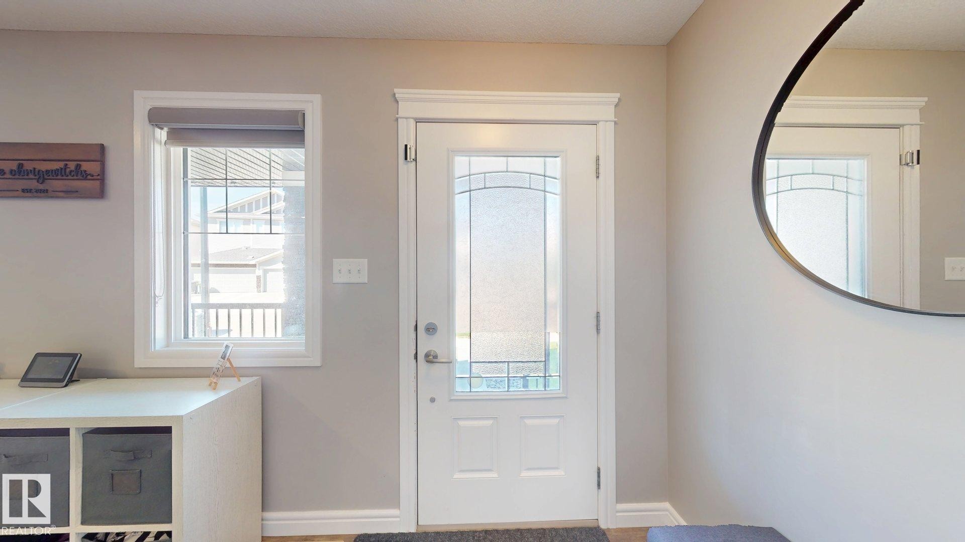 Entry door with decorative glass inserts, framed by white trim - 17359 49 Street Nw, Edmonton, AB - Indoor Photo Showing Other Room