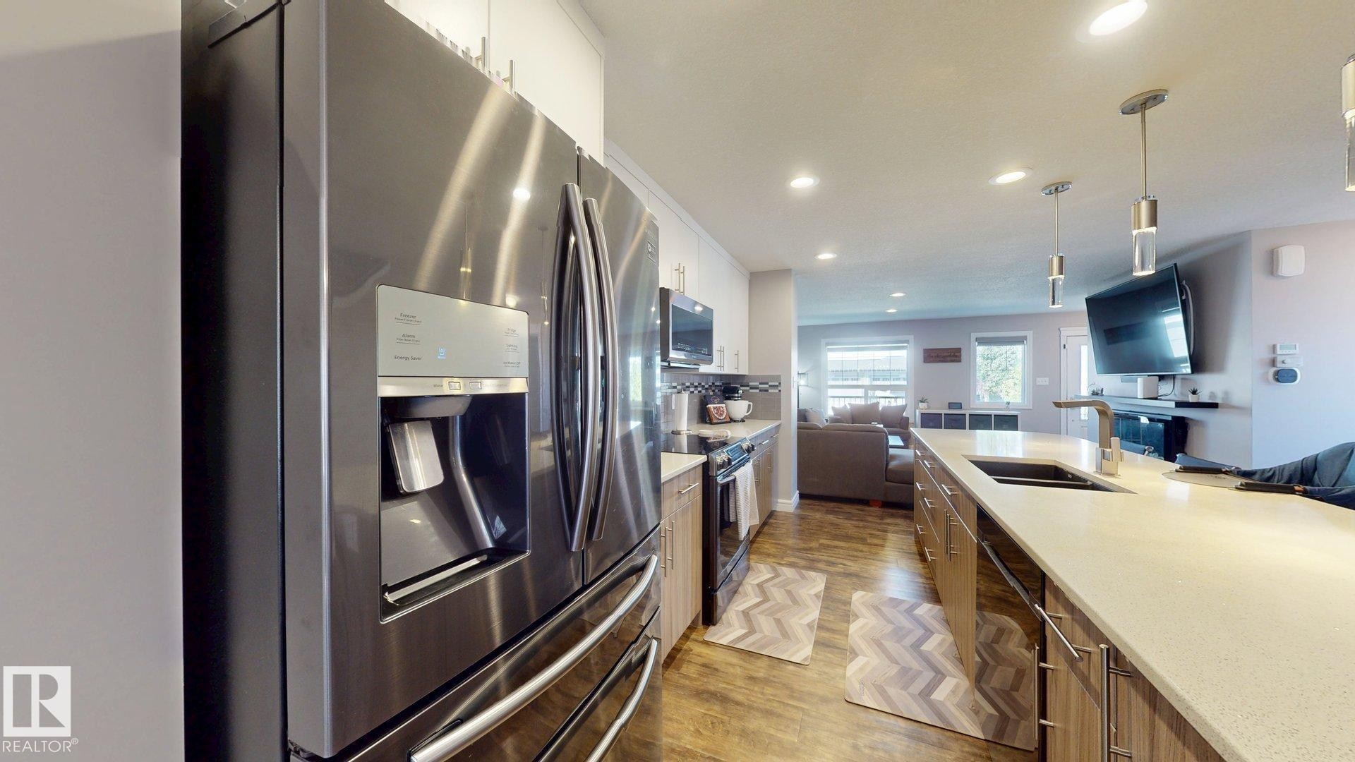 Stainless steel French door refrigerator, wood-finish flooring, recessed lighting, stone countertop, and pendant lighting - 17359 49 Street Nw, Edmonton, AB - Indoor Photo Showing Kitchen With Double Sink With Upgraded Kitchen