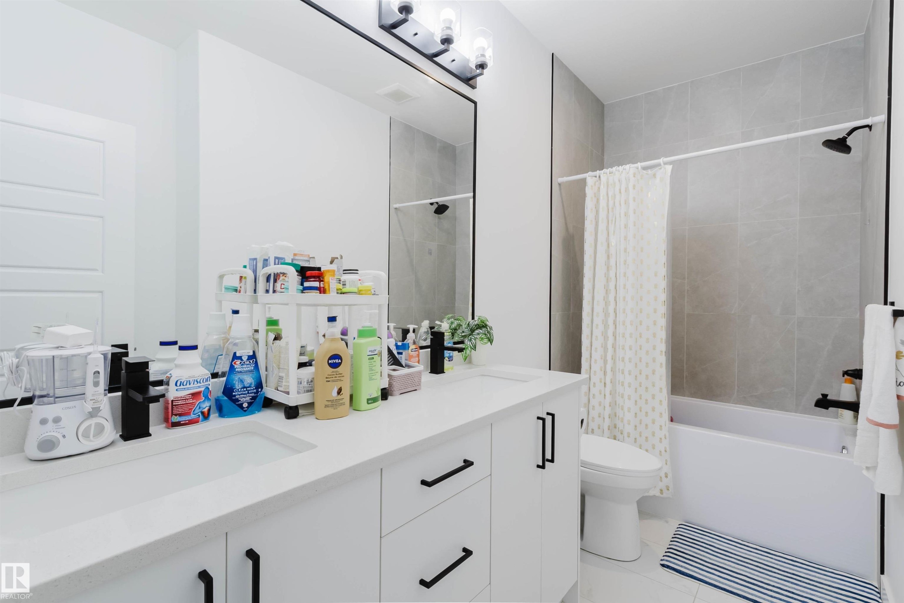 White dual vanity with integrated sinks, black hardware, and a large mirror - 104 Meadowview Way, Leduc, AB - Indoor Photo Showing Bathroom