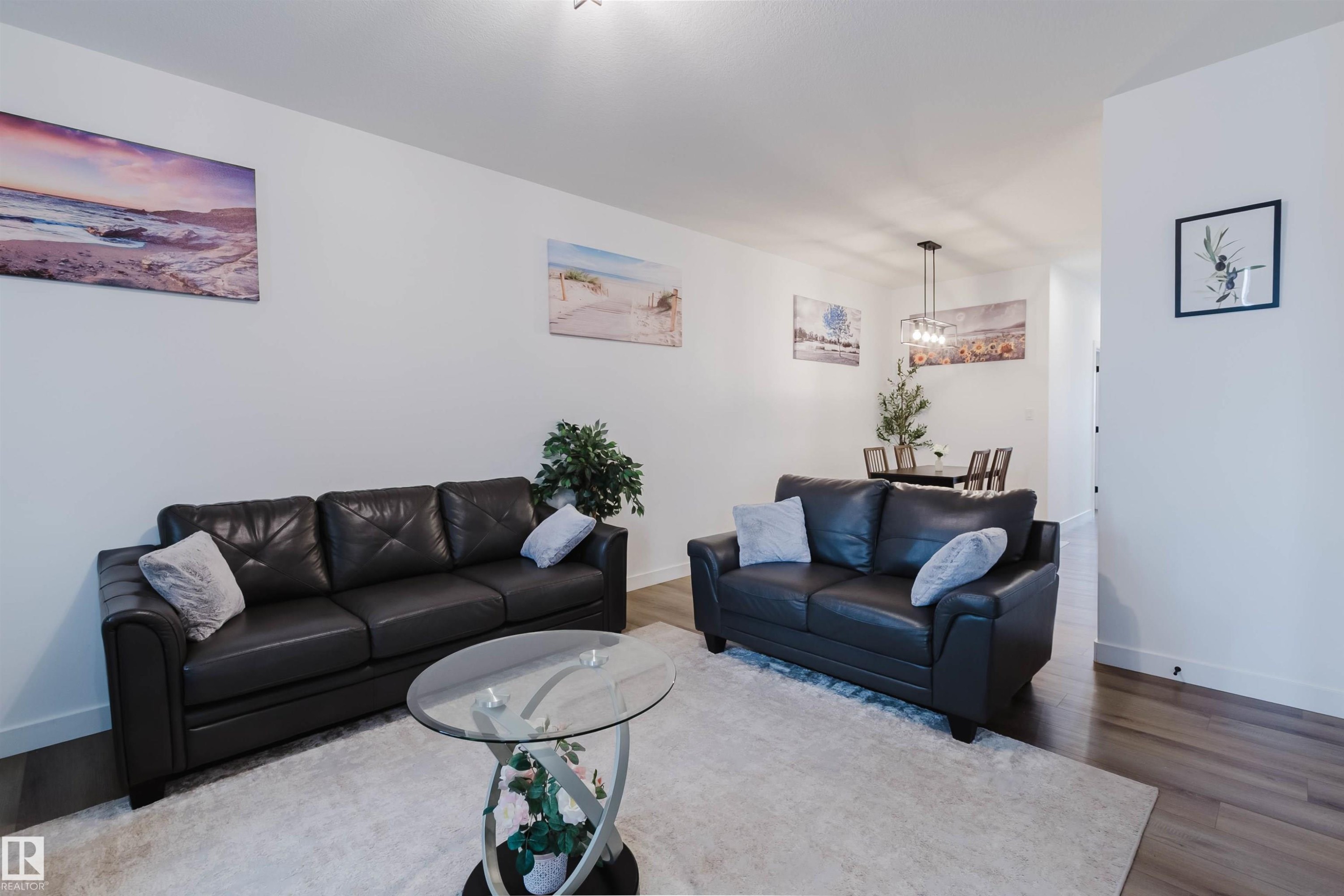 Open concept living and dining areas featuring wood-finish flooring, recessed lighting, and a contemporary dining chandelier - 104 Meadowview Way, Leduc, AB - Indoor Photo Showing Living Room