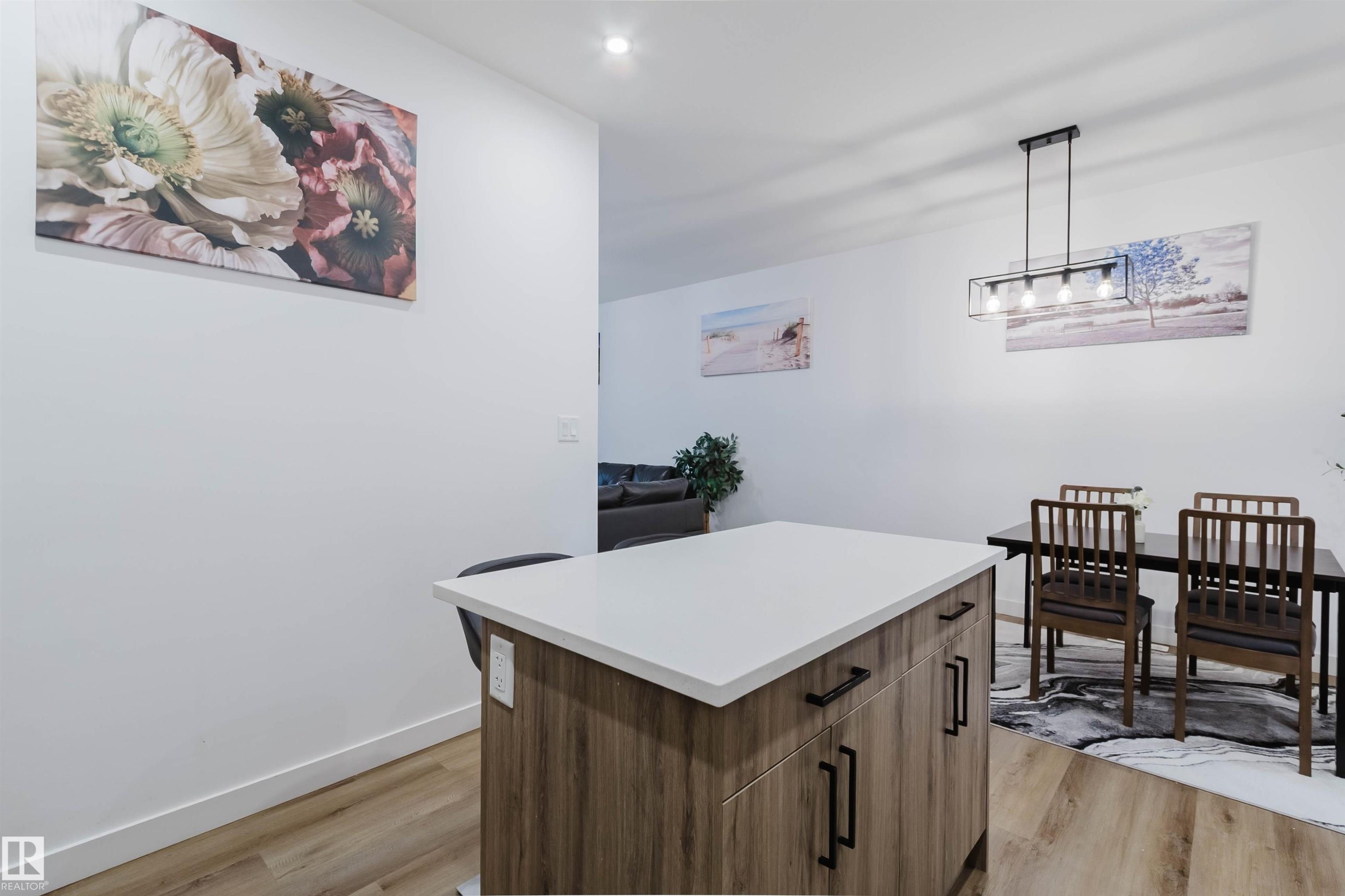 Central kitchen island with a light-toned countertop, wood-finish cabinetry, and black hardware - 104 Meadowview Way, Leduc, AB - Indoor