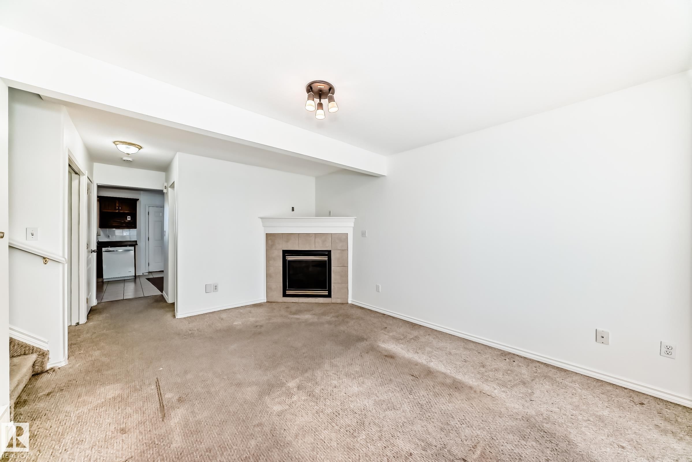 Fireplace with tile surround and mantel, flush-mount ceiling light fixture, and white painted walls - 11727 83 Street Nw, Edmonton, AB - Indoor Photo Showing Living Room With Fireplace
