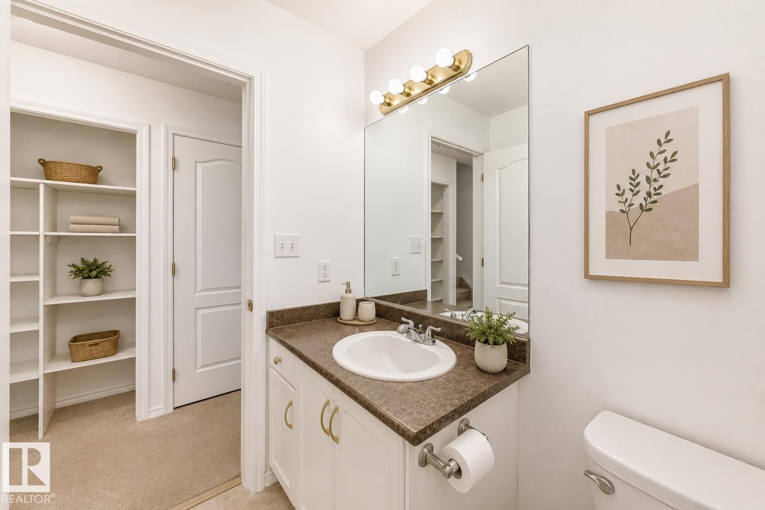 Vanity with a built-in sink and dark countertop, large wall-mounted mirror, and overhead vanity lighting - 11727 83 Street Nw, Edmonton, AB - Indoor Photo Showing Bathroom