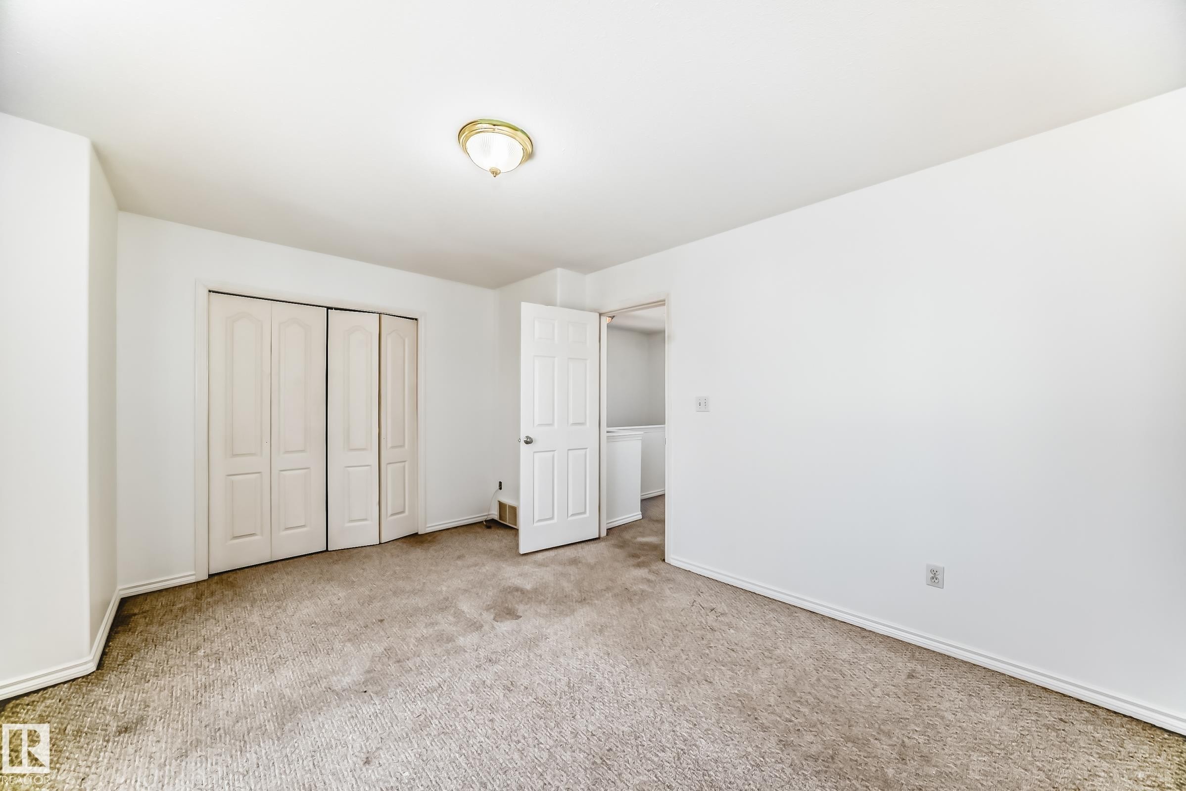 Neutral wall paint, carpet flooring, a ceiling-mounted light fixture, and bifold closet doors - 11727 83 Street Nw, Edmonton, AB - Indoor Photo Showing Other Room