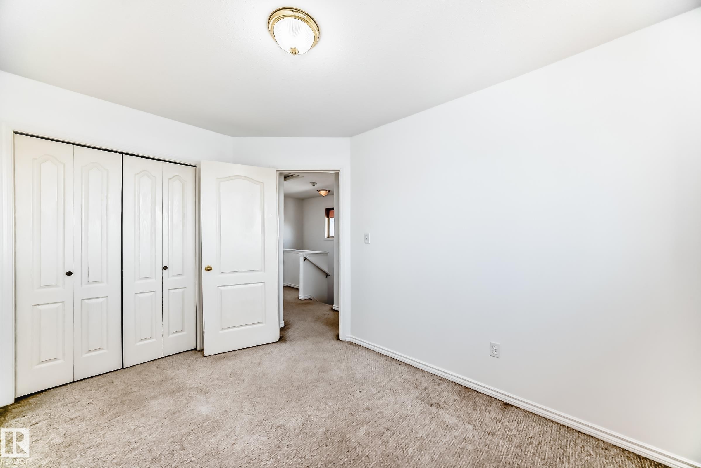 Neutral-toned carpeting, white walls, white bi-fold closet doors, and an overhead flush-mount light fixture - 11727 83 Street Nw, Edmonton, AB - Indoor Photo Showing Other Room