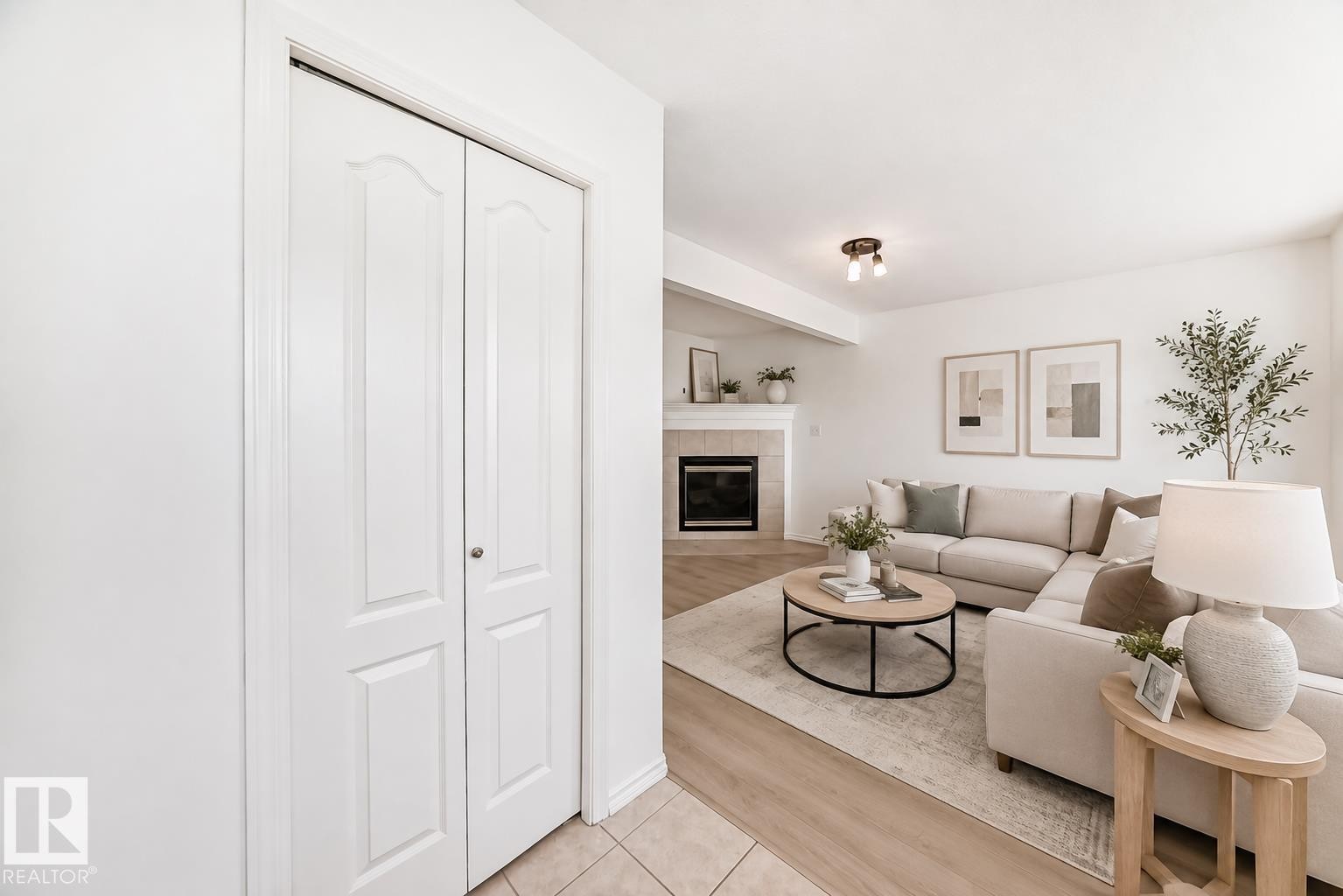 Virtually staged room with illustrating potential of room with furniture, decor and new flooring show a bright, open-concept living area featuring a wood-finish plank floor, neutral paint throughout, and abundant natural light - 11727 83 Street Nw, Edmonton, AB - Indoor Photo Showing Living Room With Fireplace
