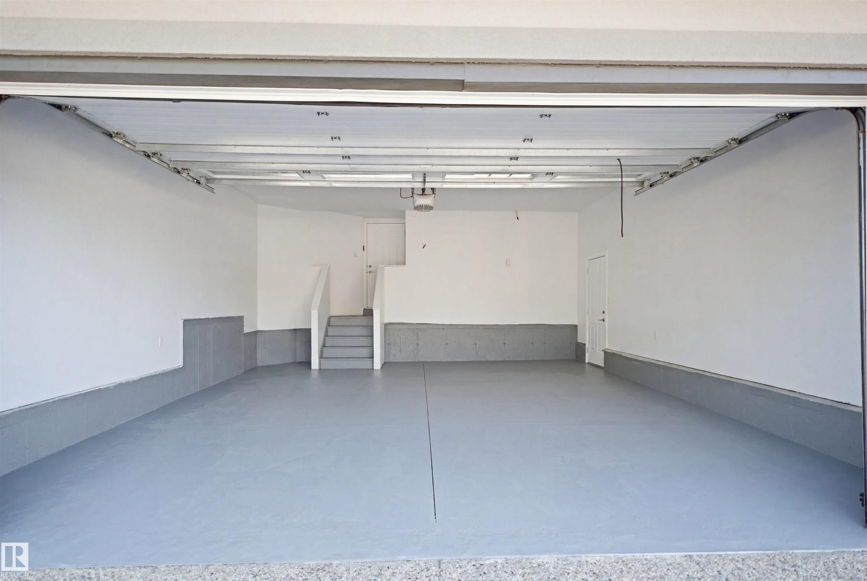Expansive garage with painted concrete flooring, clean white walls, and a convenient interior access door - 427 Windermere Road Nw, Edmonton, AB - Indoor Photo Showing Garage