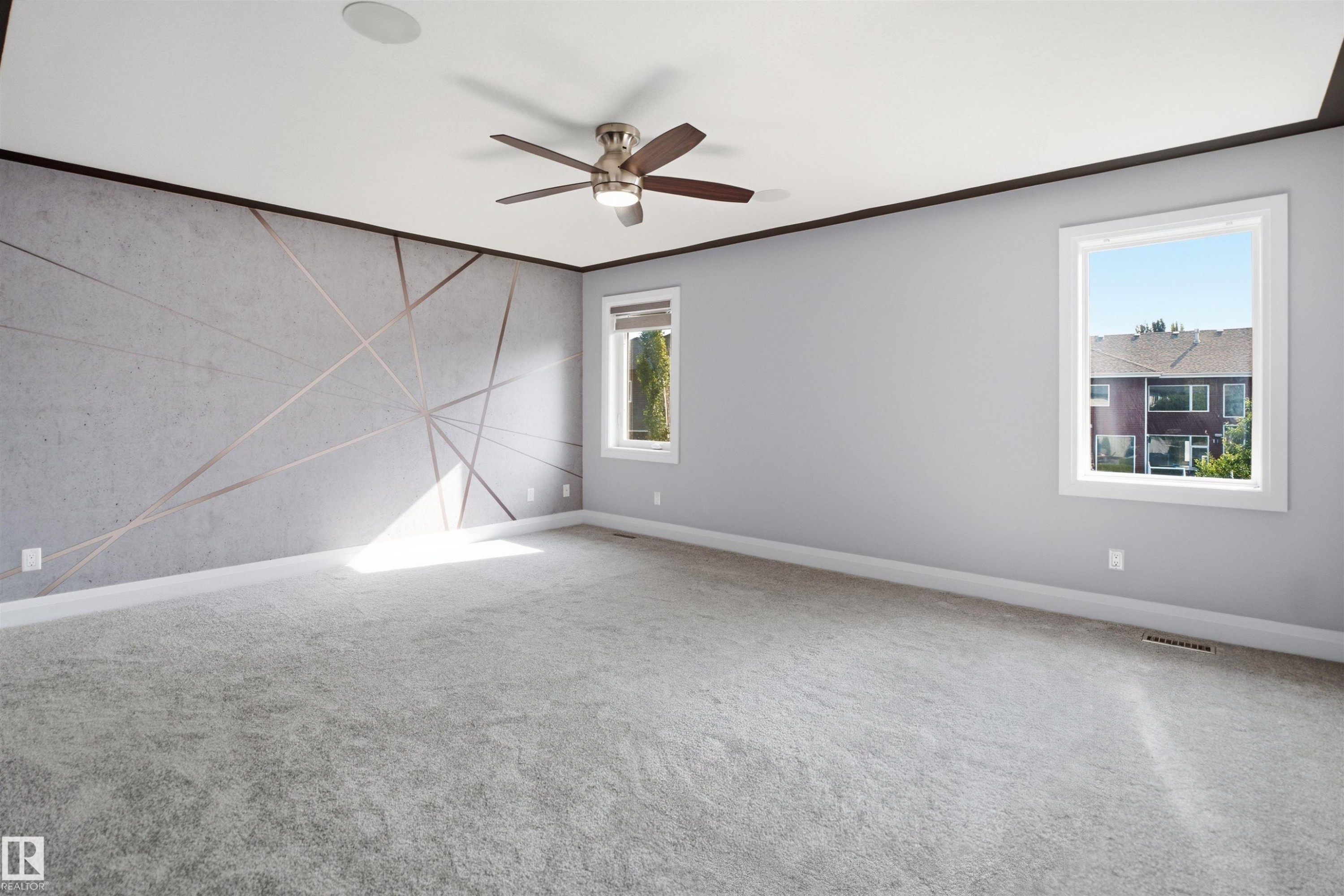 Spacious room with plush carpeting, two windows, a ceiling fan, and an accent wall featuring a geometric design - 427 Windermere Road Nw, Edmonton, AB - Indoor Photo Showing Other Room