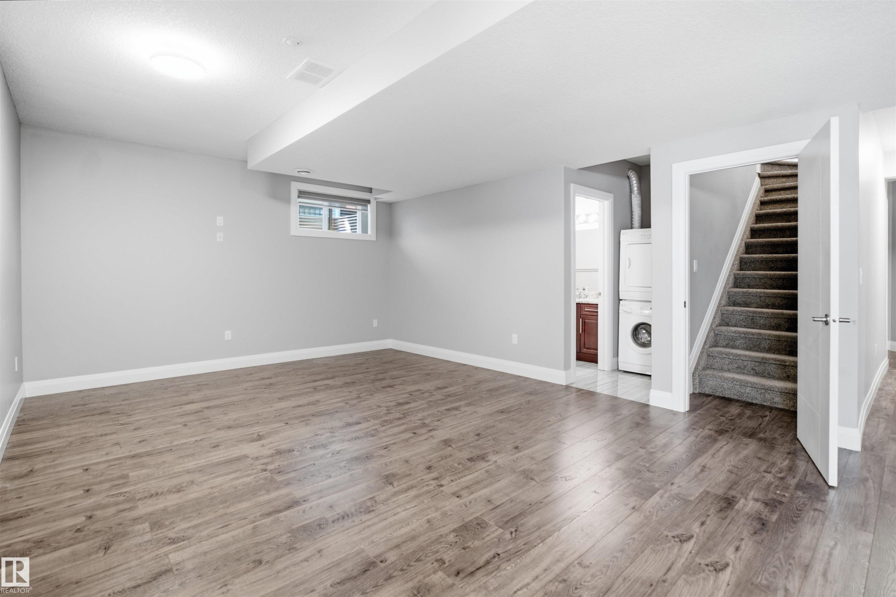 Spacious open area with wood-finish flooring, recessed ceiling light, and a window - 427 Windermere Road Nw, Edmonton, AB - Indoor Photo Showing Other Room