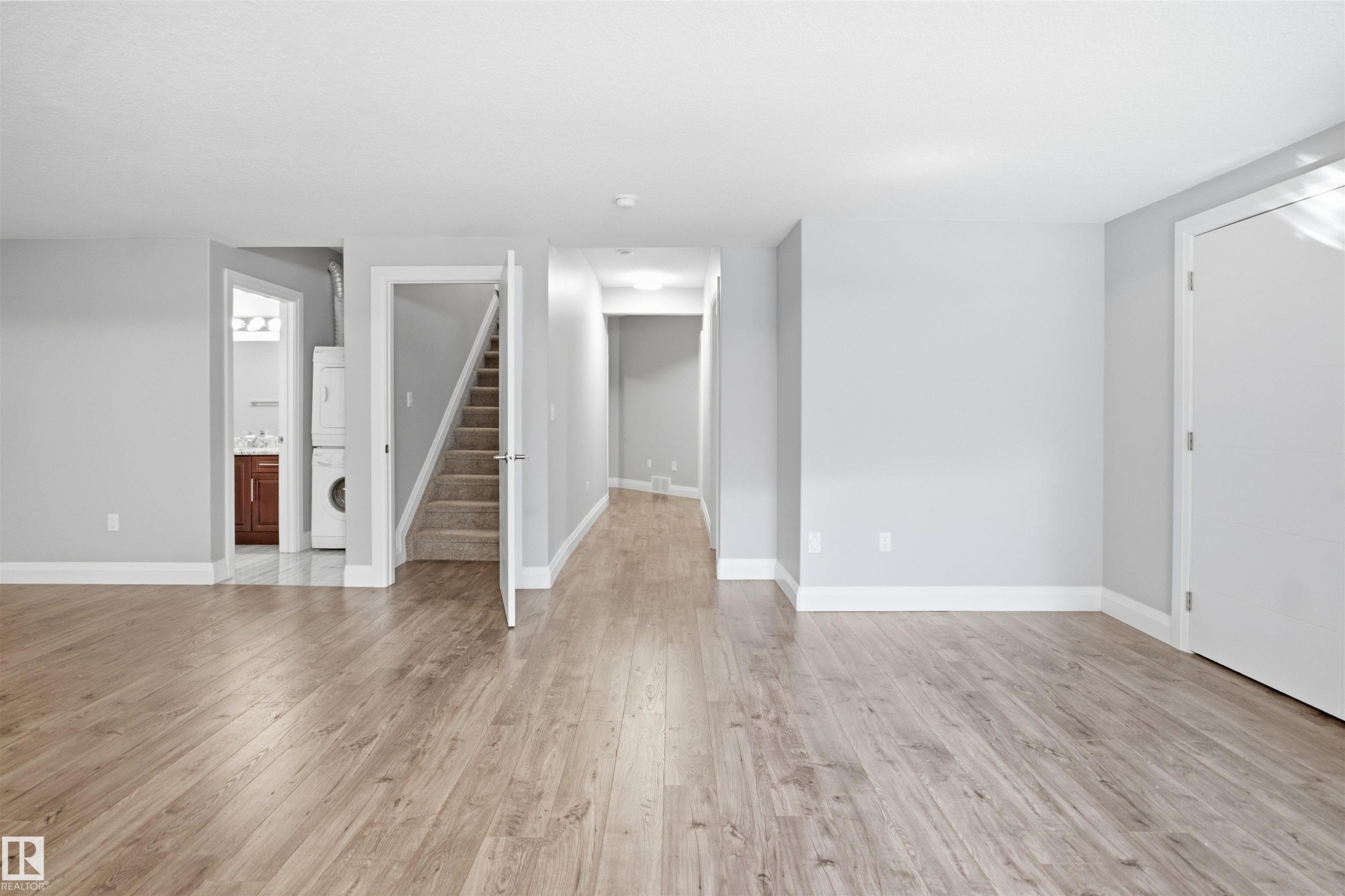 Wood-finish flooring throughout, light gray wall paint, white trim, and white interior doors - 427 Windermere Road Nw, Edmonton, AB - Indoor Photo Showing Other Room