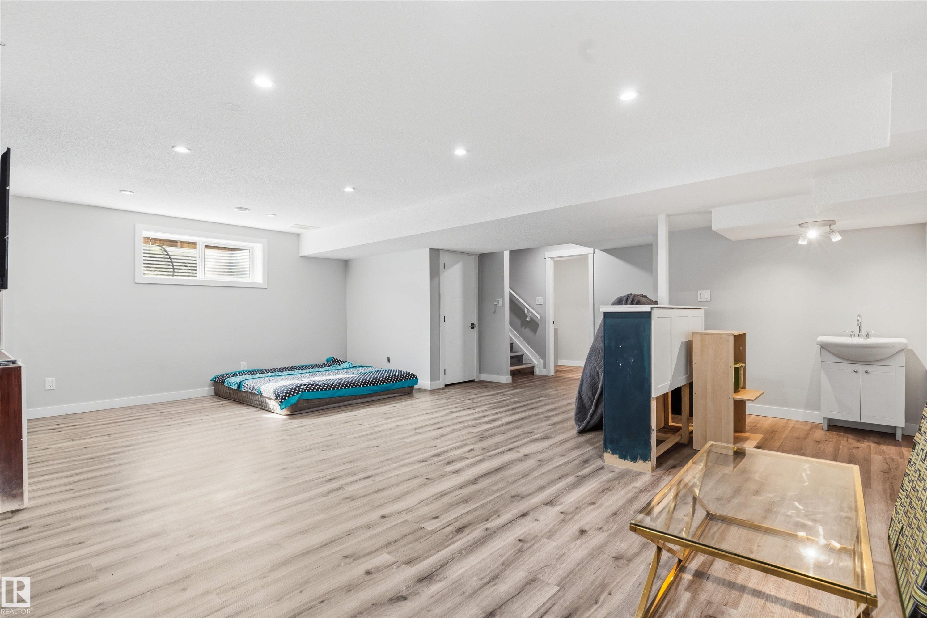 Spacious room featuring wood-finish flooring, recessed lighting, and a window with blinds - 1103 26 Avenue Nw, Edmonton, AB