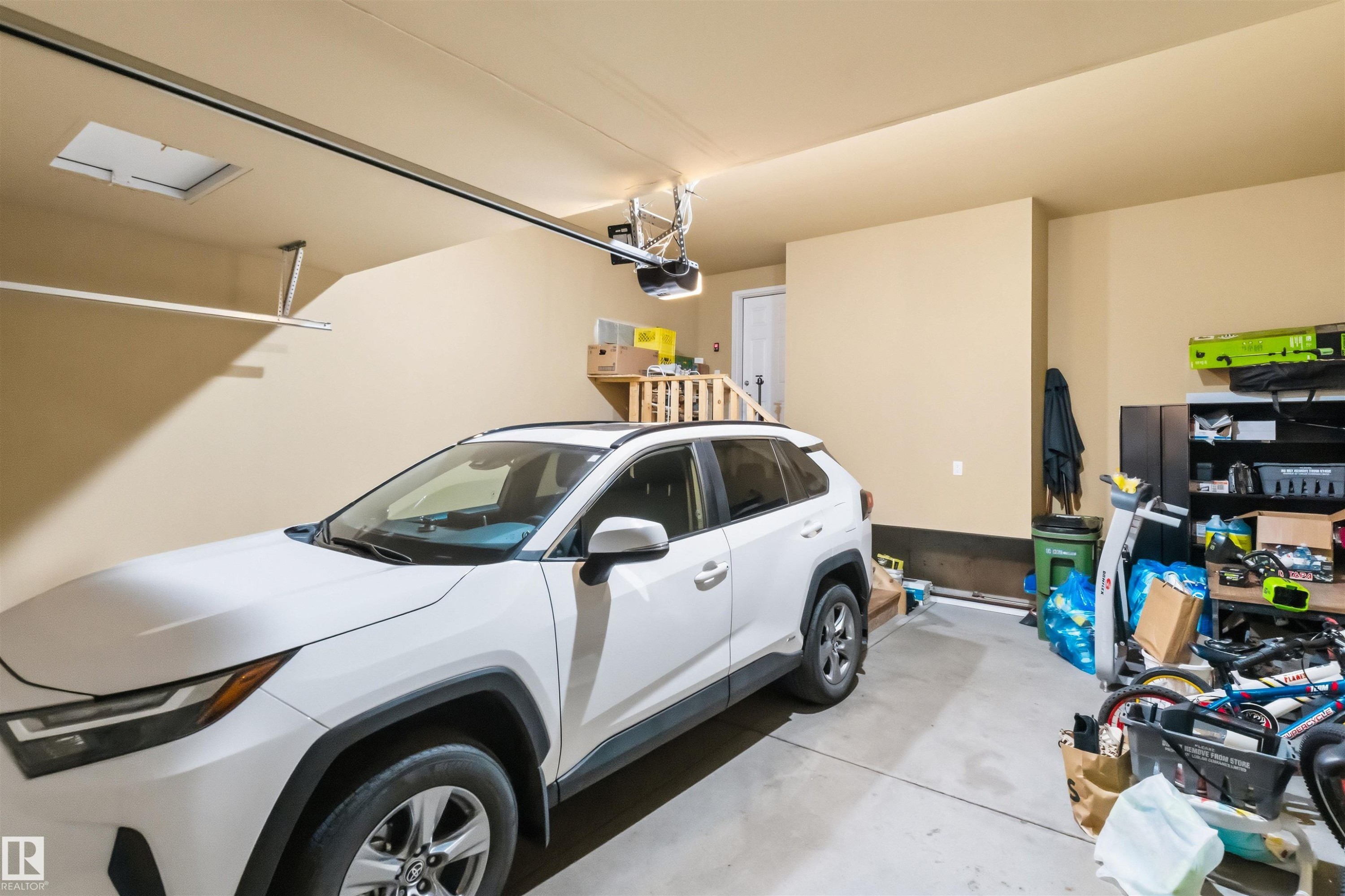 Attached garage featuring painted walls, concrete flooring, and an overhead garage door opener - 1103 26 Avenue Nw, Edmonton, AB