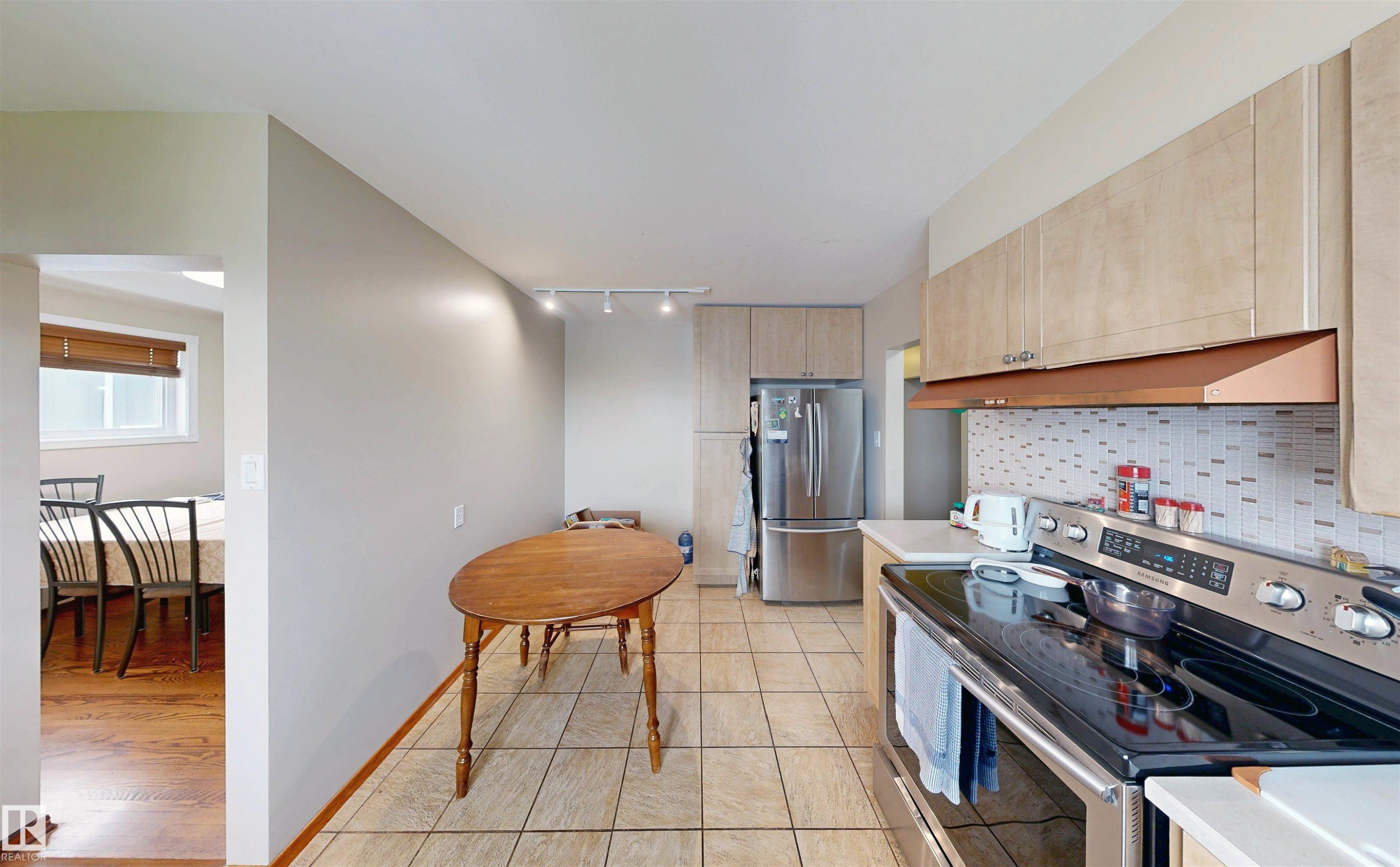 Kitchen featuring tile flooring, light-toned cabinetry, stainless steel appliances, and a tiled backsplash - 9531 74 Street Nw, Edmonton, AB - Indoor Photo Showing Kitchen