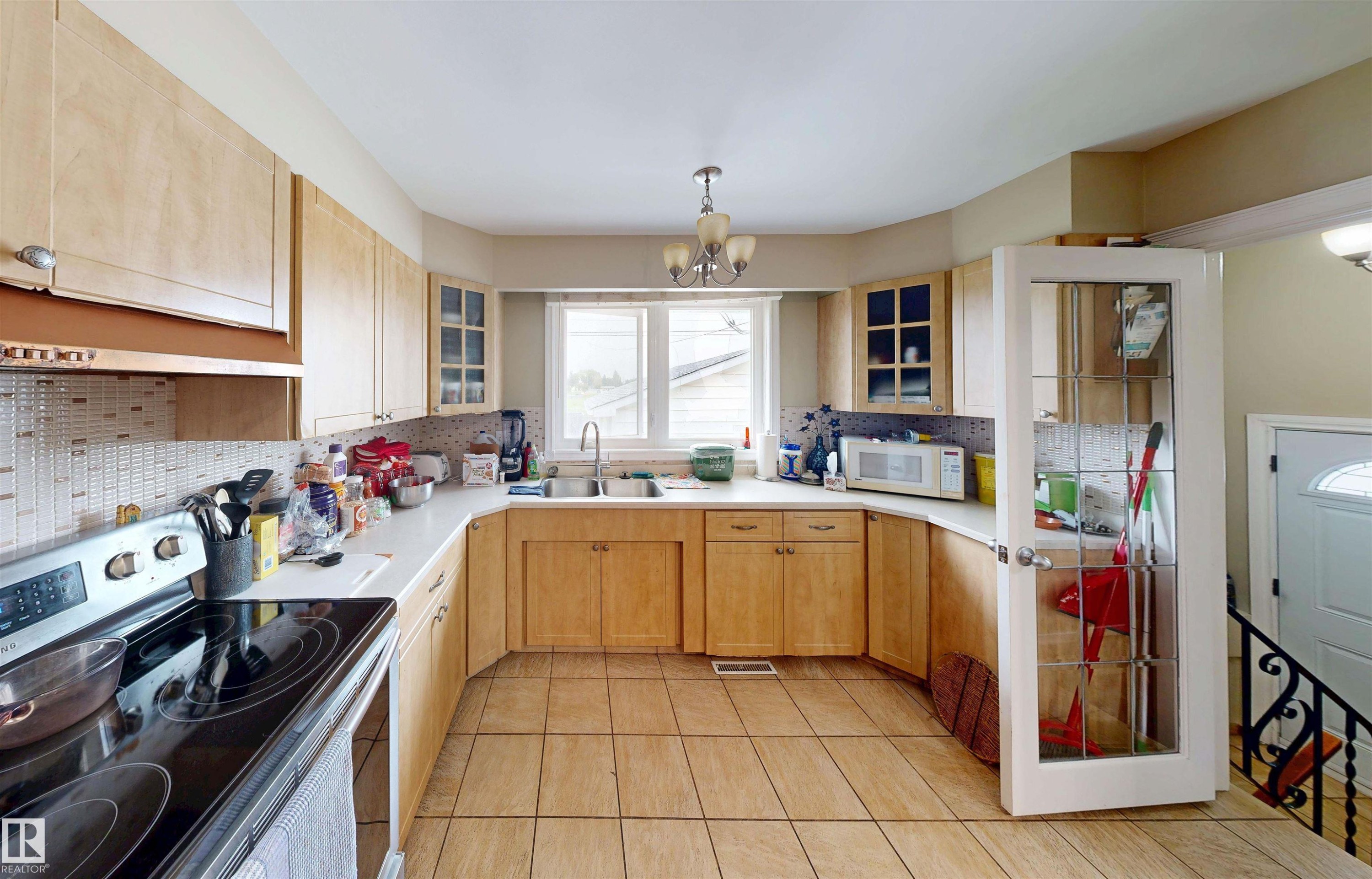 U-shaped kitchen featuring wood cabinetry, white countertops, tile flooring, and a patterned tile backsplash - 9531 74 Street Nw, Edmonton, AB - Indoor Photo Showing Kitchen