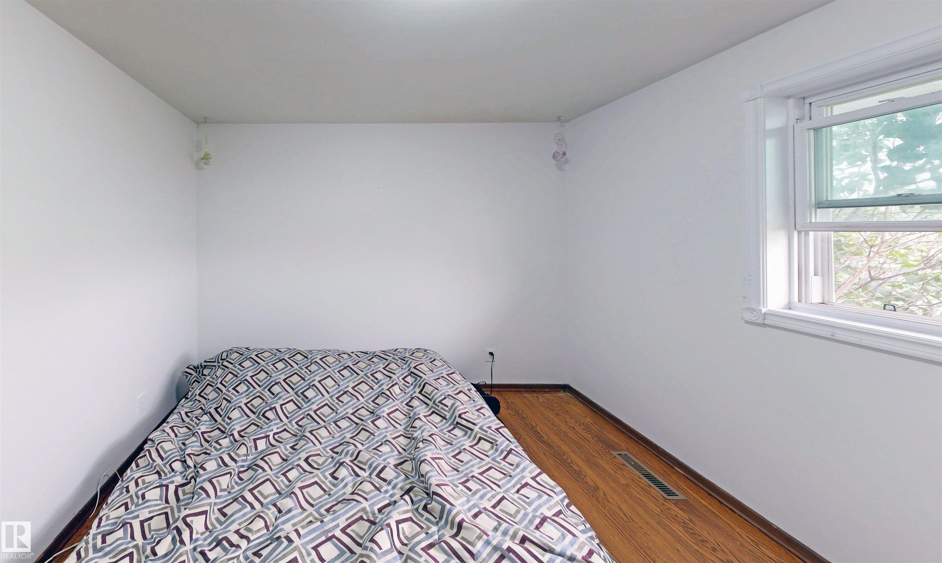 Wood-finish flooring with white walls and a white-framed window - 9531 74 Street Nw, Edmonton, AB - Indoor Photo Showing Bedroom