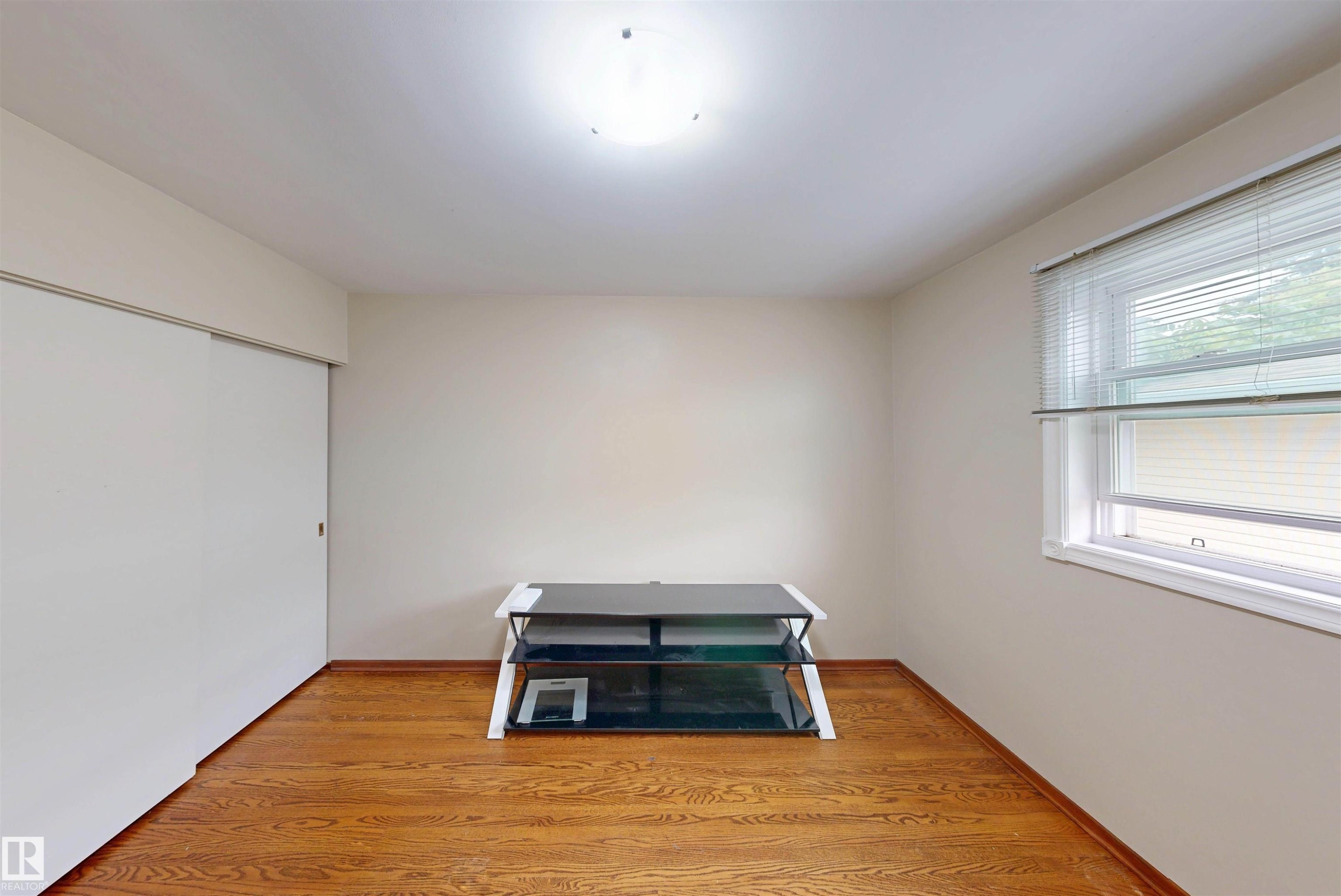 Hardwood flooring, neutral wall tones, window with horizontal blinds, and a flush mount ceiling light - 9531 74 Street Nw, Edmonton, AB - Indoor Photo Showing Other Room