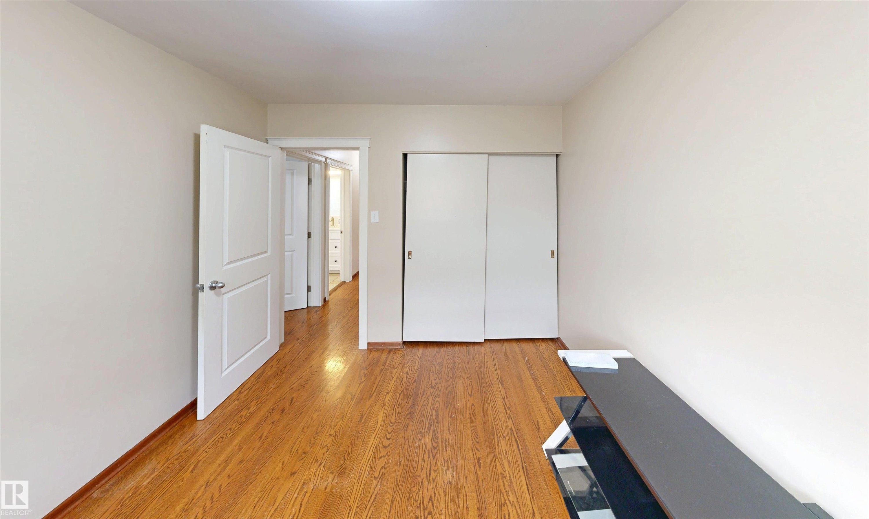 Hardwood flooring, white interior doors, and white sliding closet doors - 9531 74 Street Nw, Edmonton, AB - Indoor Photo Showing Other Room