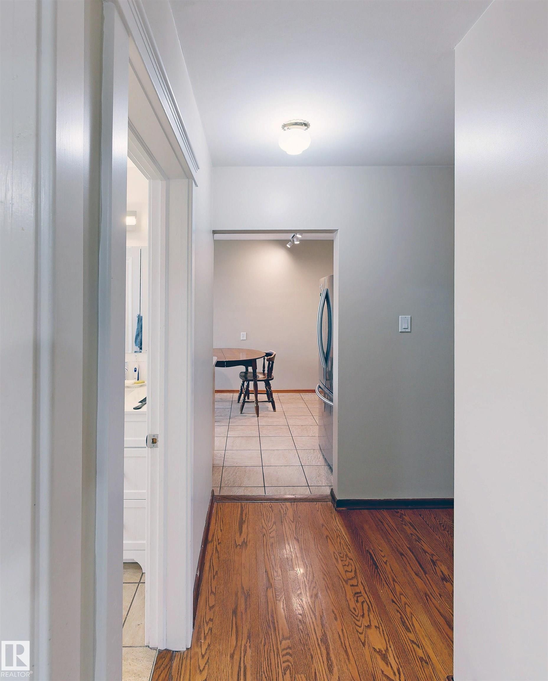 Wood-finish flooring leading to a tiled area - 9531 74 Street Nw, Edmonton, AB - Indoor Photo Showing Other Room