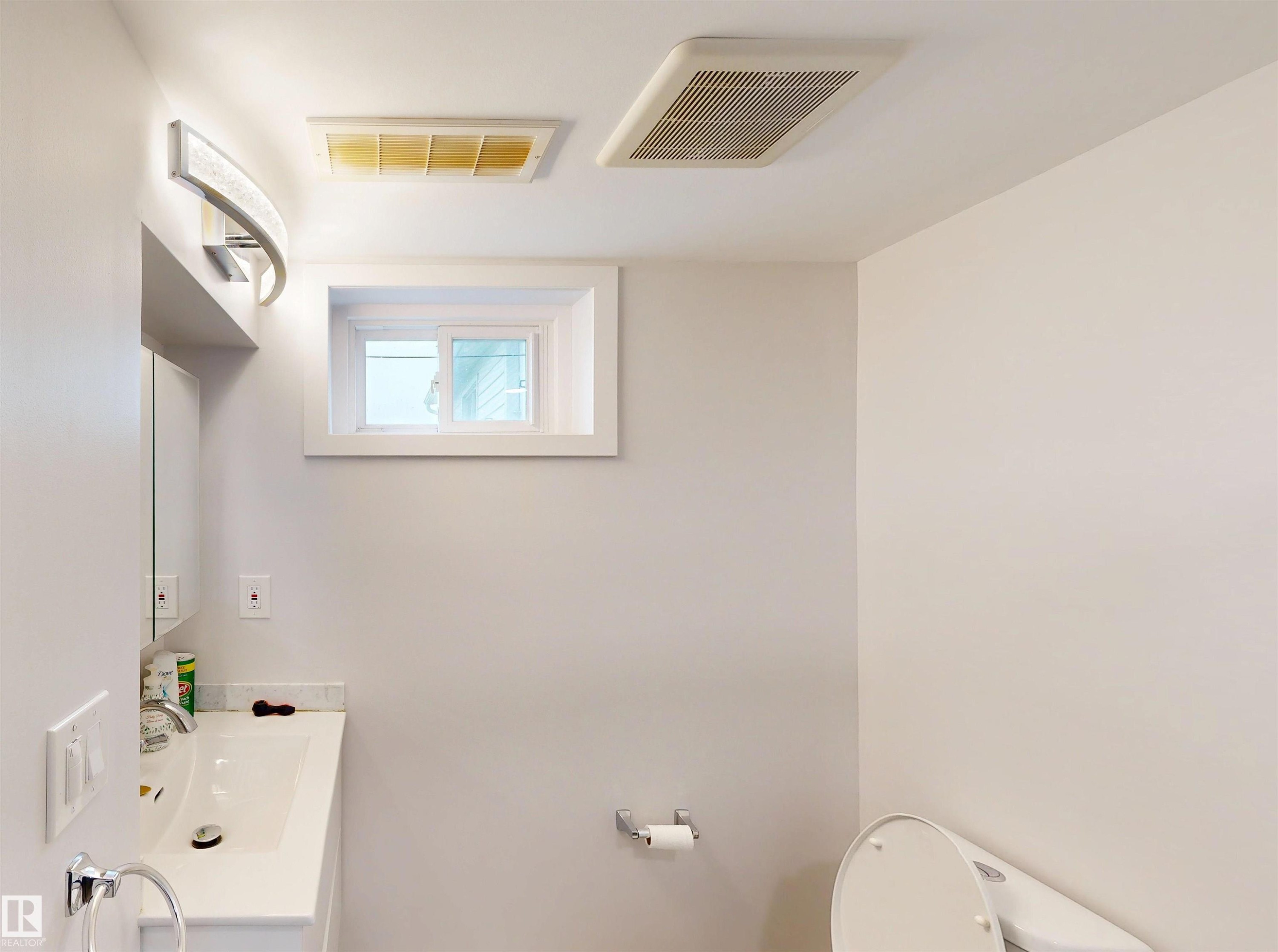 White vanity with an integrated sink and chrome faucet, under-window placement - 9531 74 Street Nw, Edmonton, AB - Indoor Photo Showing Bathroom