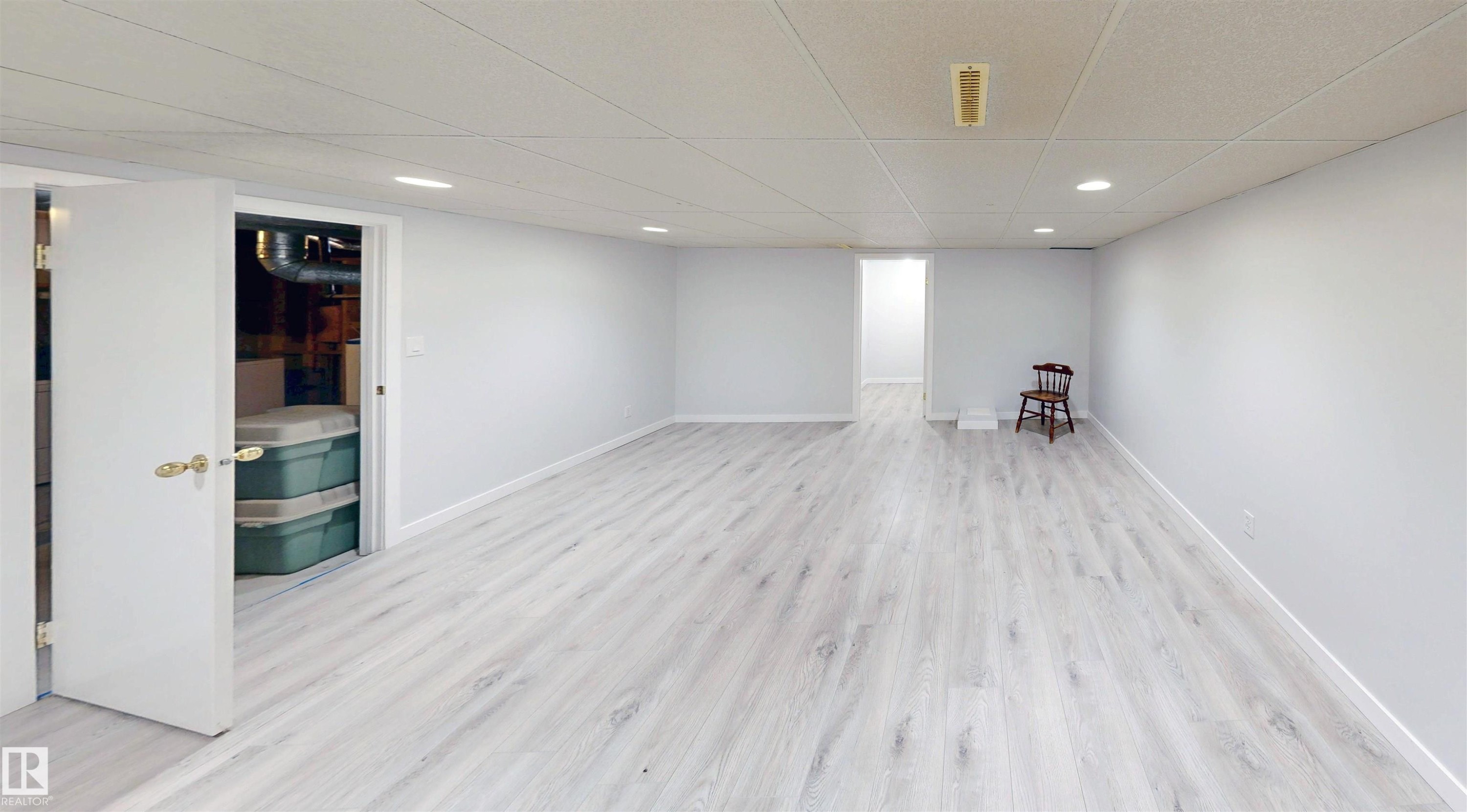 Spacious room featuring wood-finish flooring, white walls, and recessed lighting - 9531 74 Street Nw, Edmonton, AB - Indoor