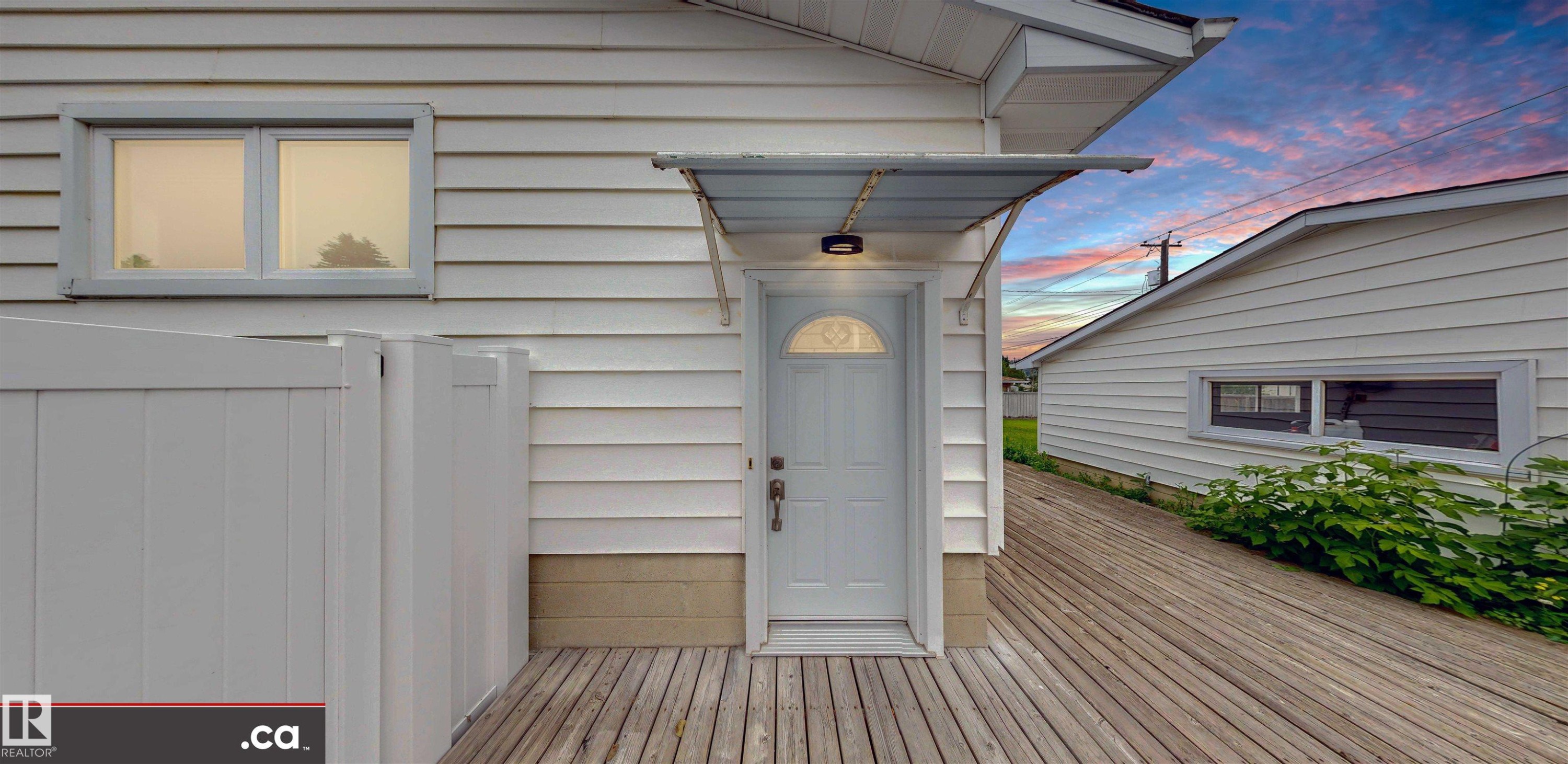 White horizontal siding with a window, outdoor light fixture, and a white entry door with an arched window - 9531 74 Street Nw, Edmonton, AB - Outdoor With Exterior