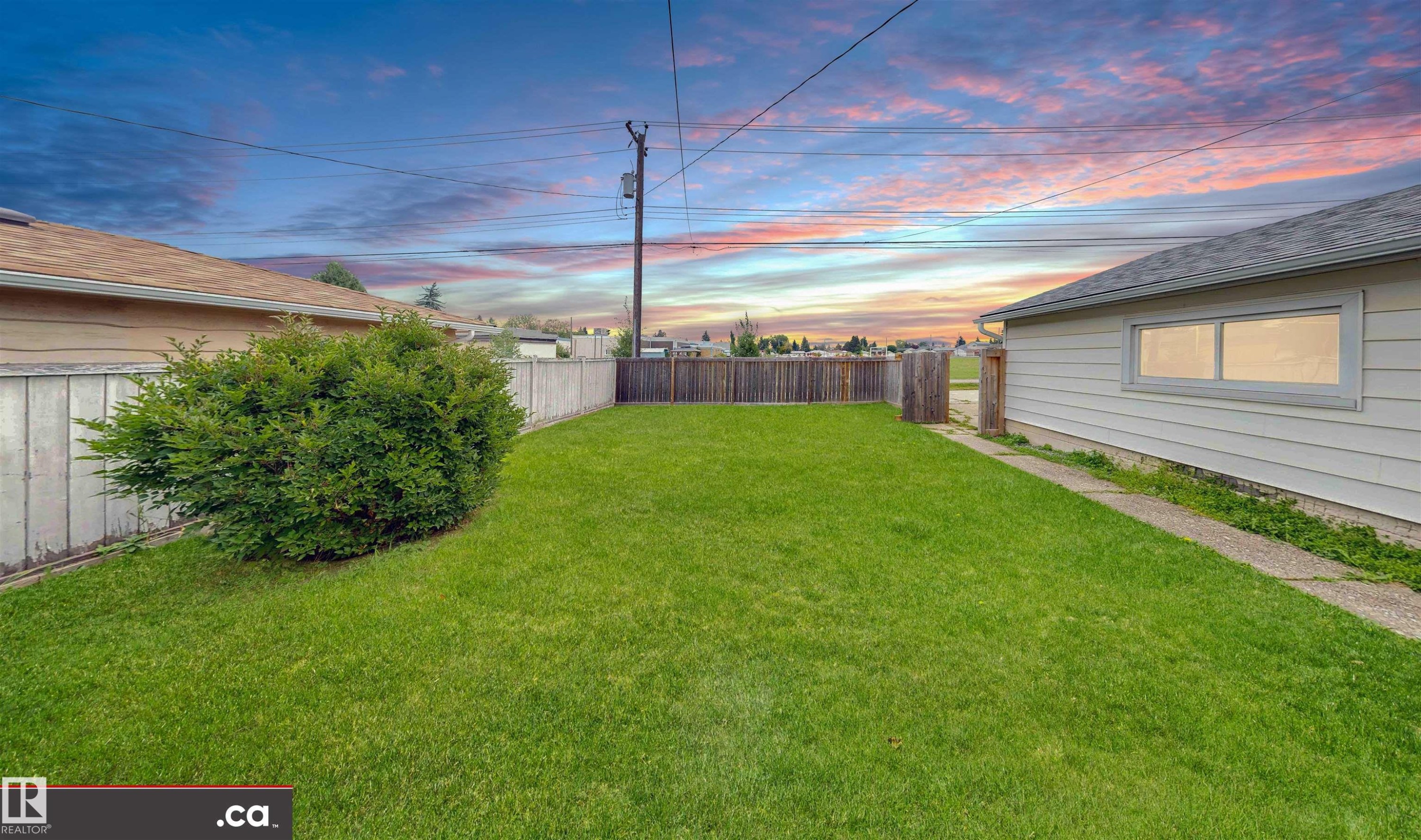 Expansive lawn area with a perimeter fence, mature landscaping, and a detached structure with siding - 9531 74 Street Nw, Edmonton, AB - Outdoor