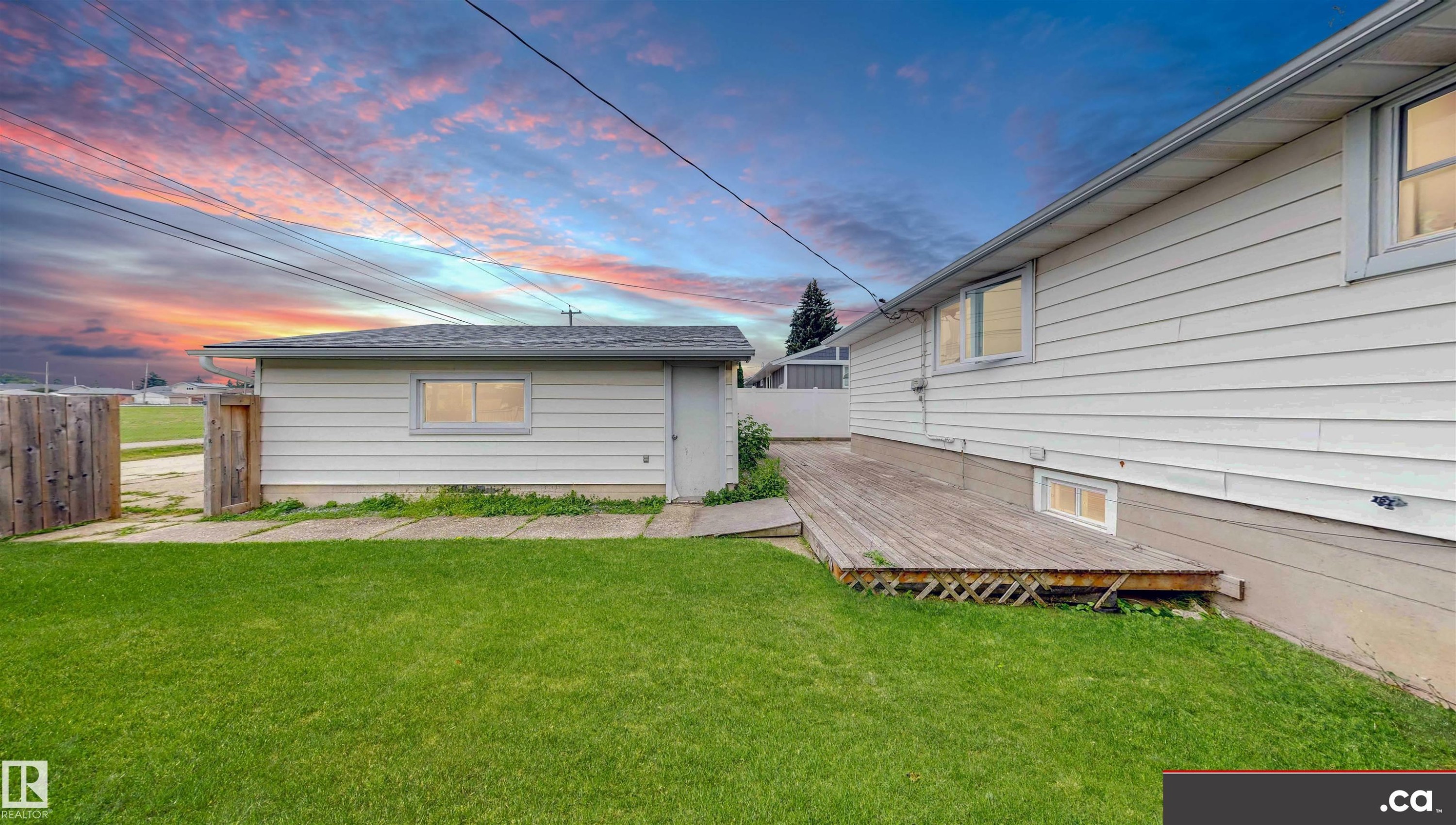 Spacious grassy yard, detached structure with window, wood-plank deck, and exterior wall with multiple windows - 9531 74 Street Nw, Edmonton, AB - Outdoor With Exterior