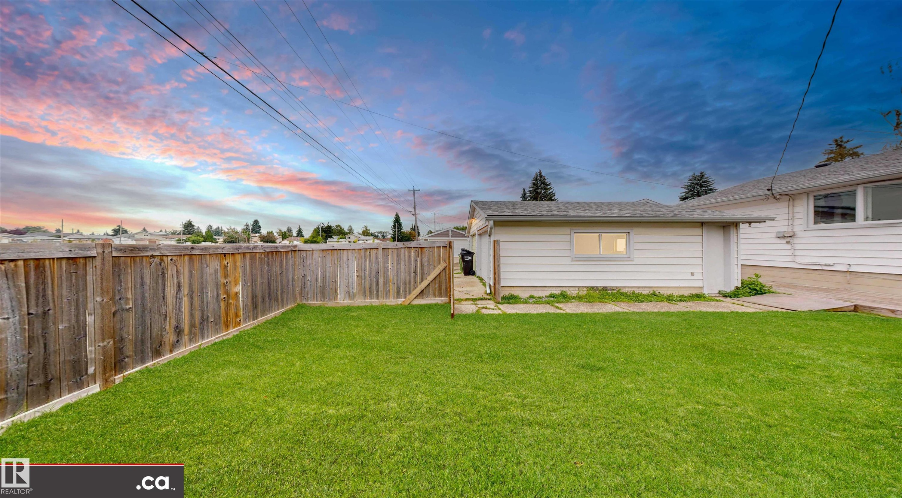 Expansive lawn area with wood perimeter fencing and a single-story detached garage - 9531 74 Street Nw, Edmonton, AB - Outdoor