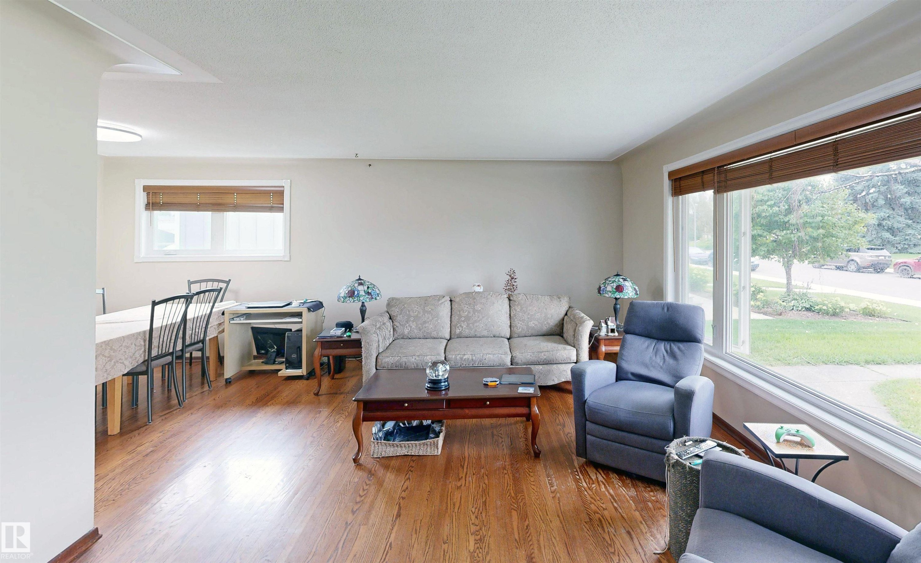 Hardwood flooring throughout, large picture window with brown blinds, additional window with brown blinds, neutral wall paint, and recessed lighting - 9531 74 Street Nw, Edmonton, AB - Indoor Photo Showing Living Room