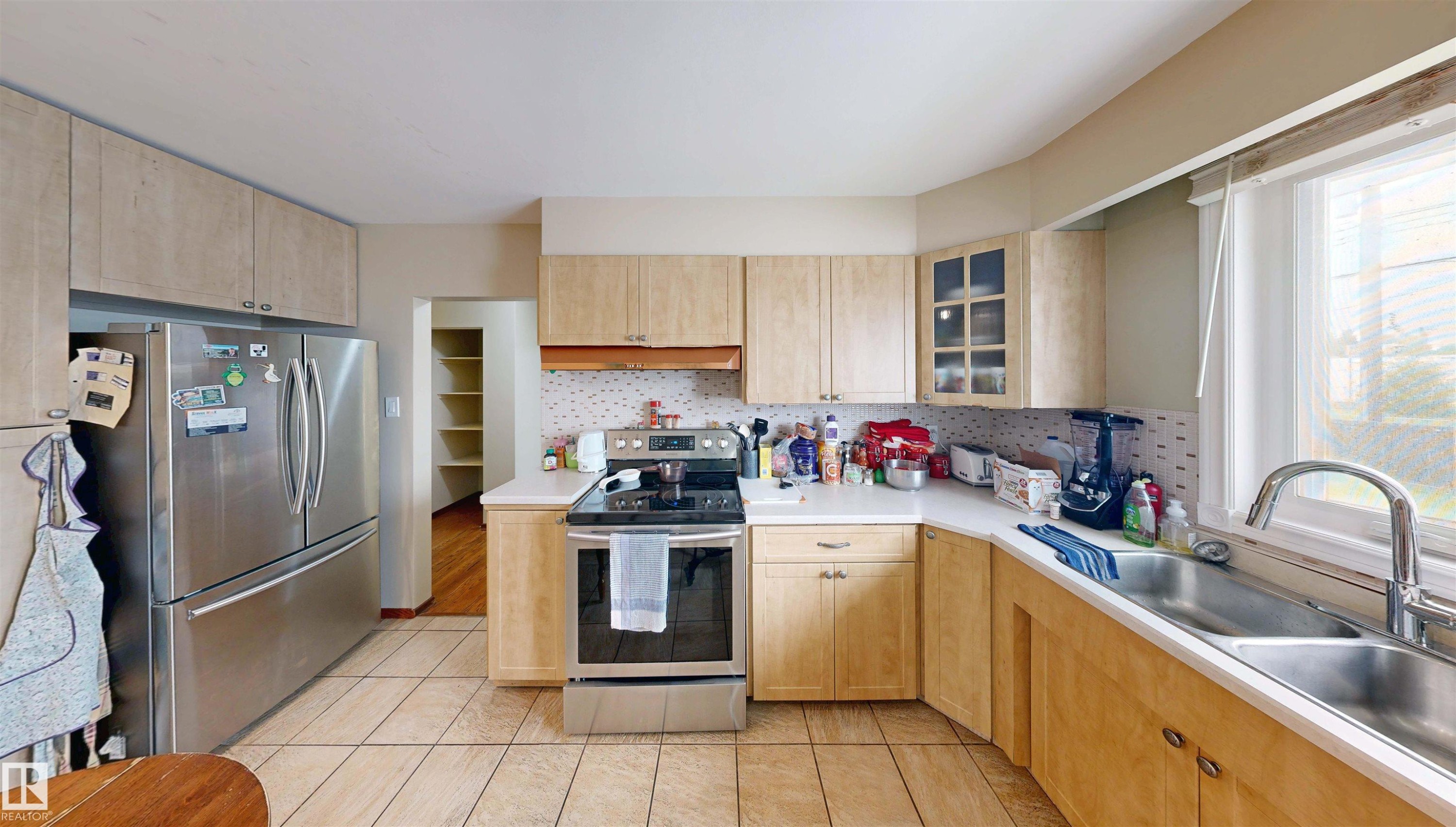 Kitchen featuring light wood-finish cabinetry, tile flooring, stainless steel appliances, and a double basin sink - 9531 74 Street Nw, Edmonton, AB - Indoor Photo Showing Kitchen With Double Sink