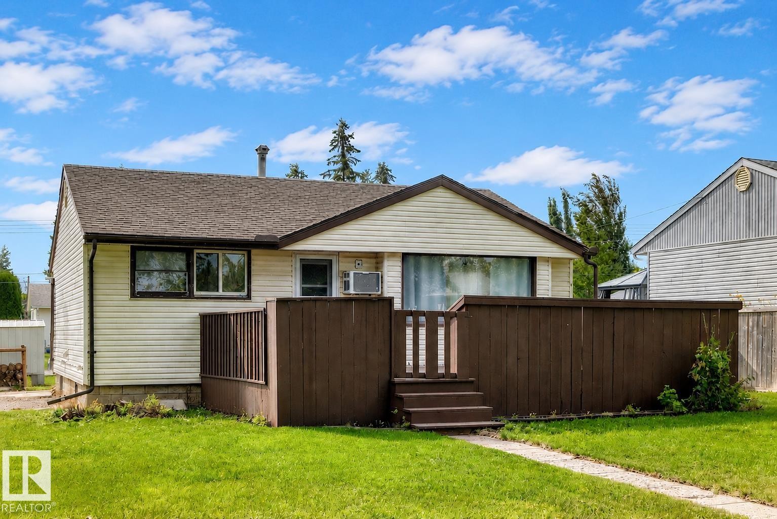 Exterior featuring horizontal vinyl siding, brown wood deck with steps, a shingled roof, and a concrete pathway - 50 Rocque, Fort Saskatchewan, AB - Outdoor