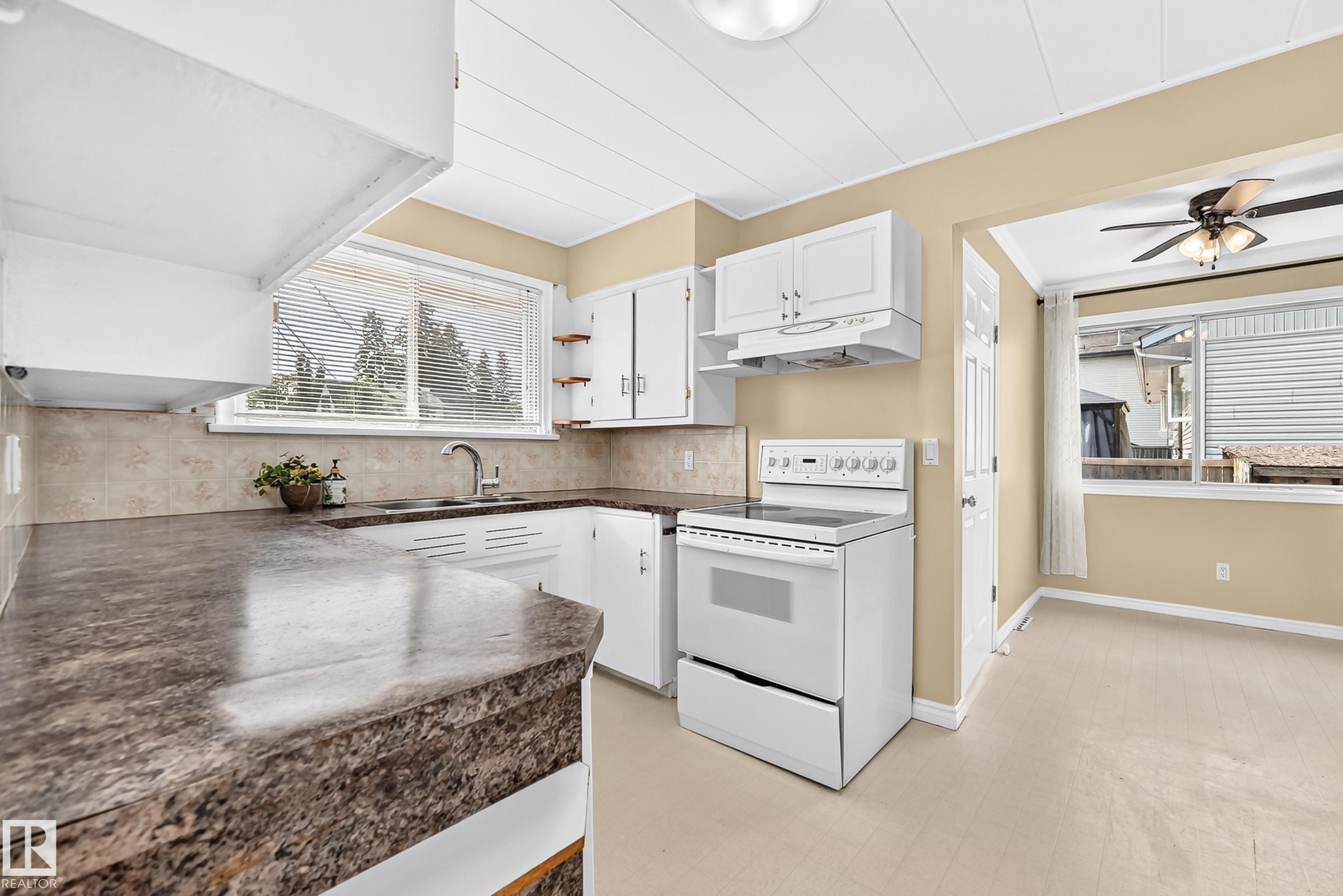 Kitchen featuring white cabinetry, stone-look countertops, a built-in range, a stainless steel sink, and tile backsplash - 50 Rocque, Fort Saskatchewan, AB - Indoor Photo Showing Kitchen With Double Sink
