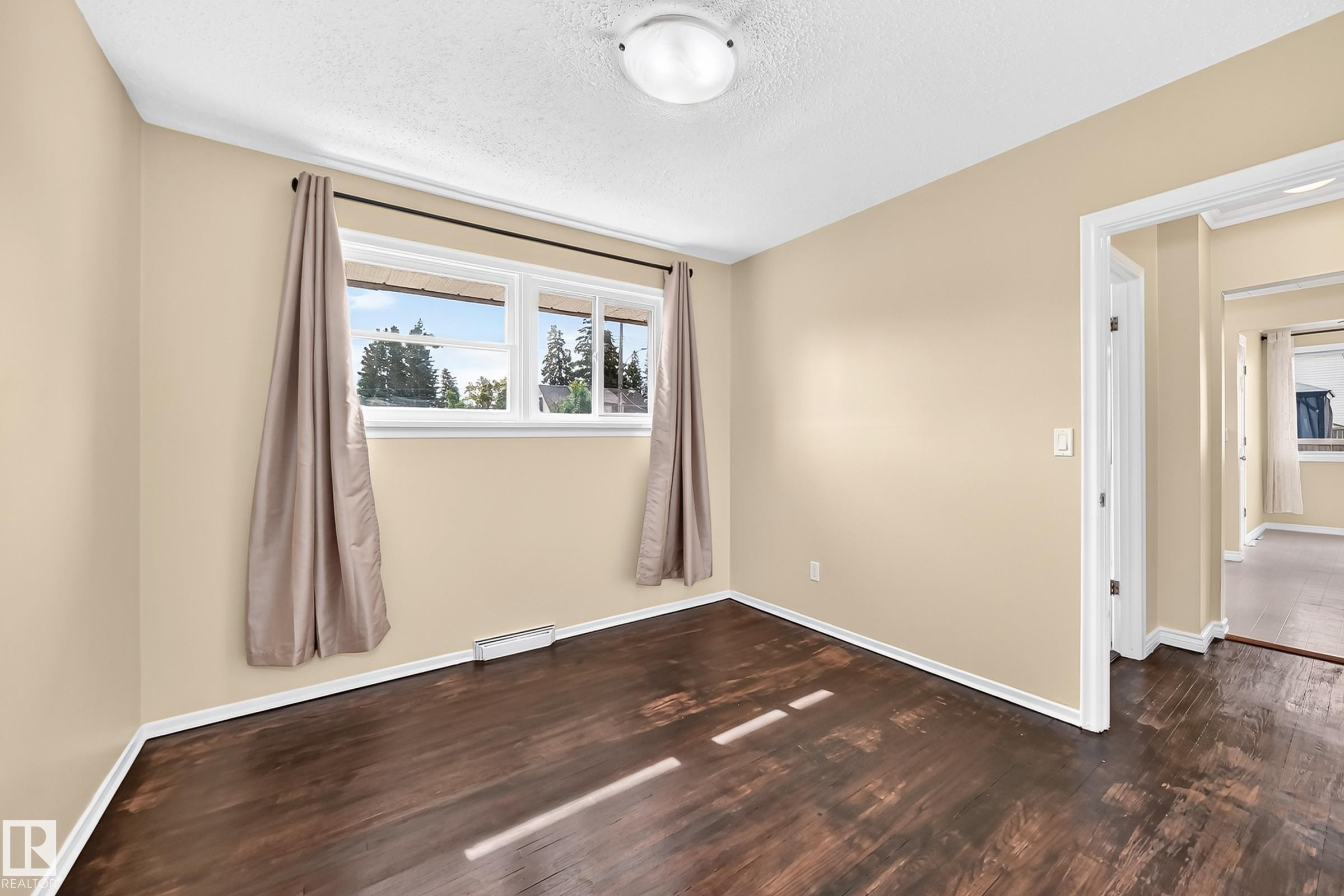 Dual windows with white trim, wood-finish flooring, and light-toned wall paint - 50 Rocque, Fort Saskatchewan, AB - Indoor Photo Showing Other Room