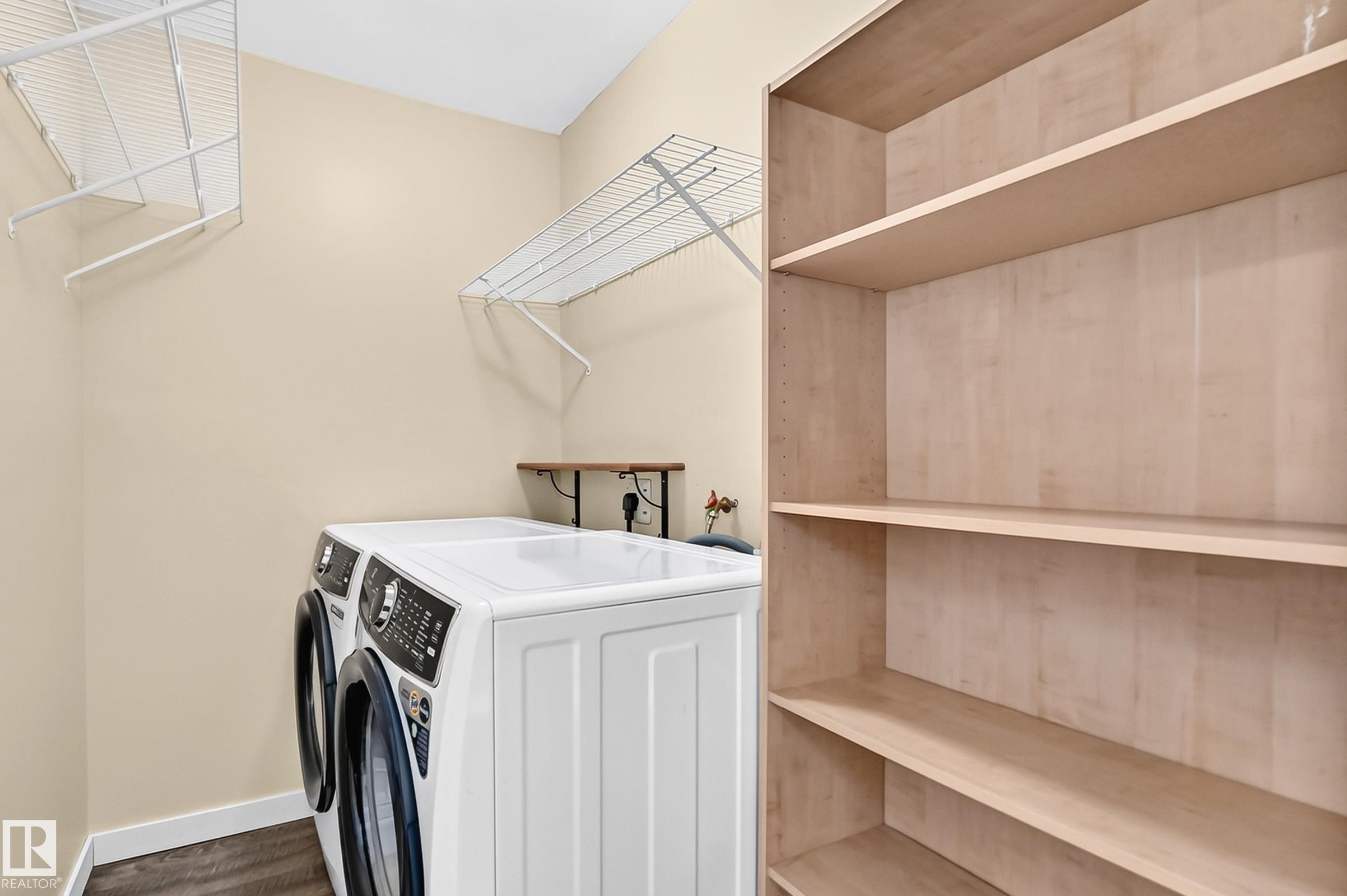 Wood-finish flooring with built-in shelving, a wall-mounted drying rack, and a mounted wood shelf - 50 Rocque, Fort Saskatchewan, AB - Indoor Photo Showing Laundry Room