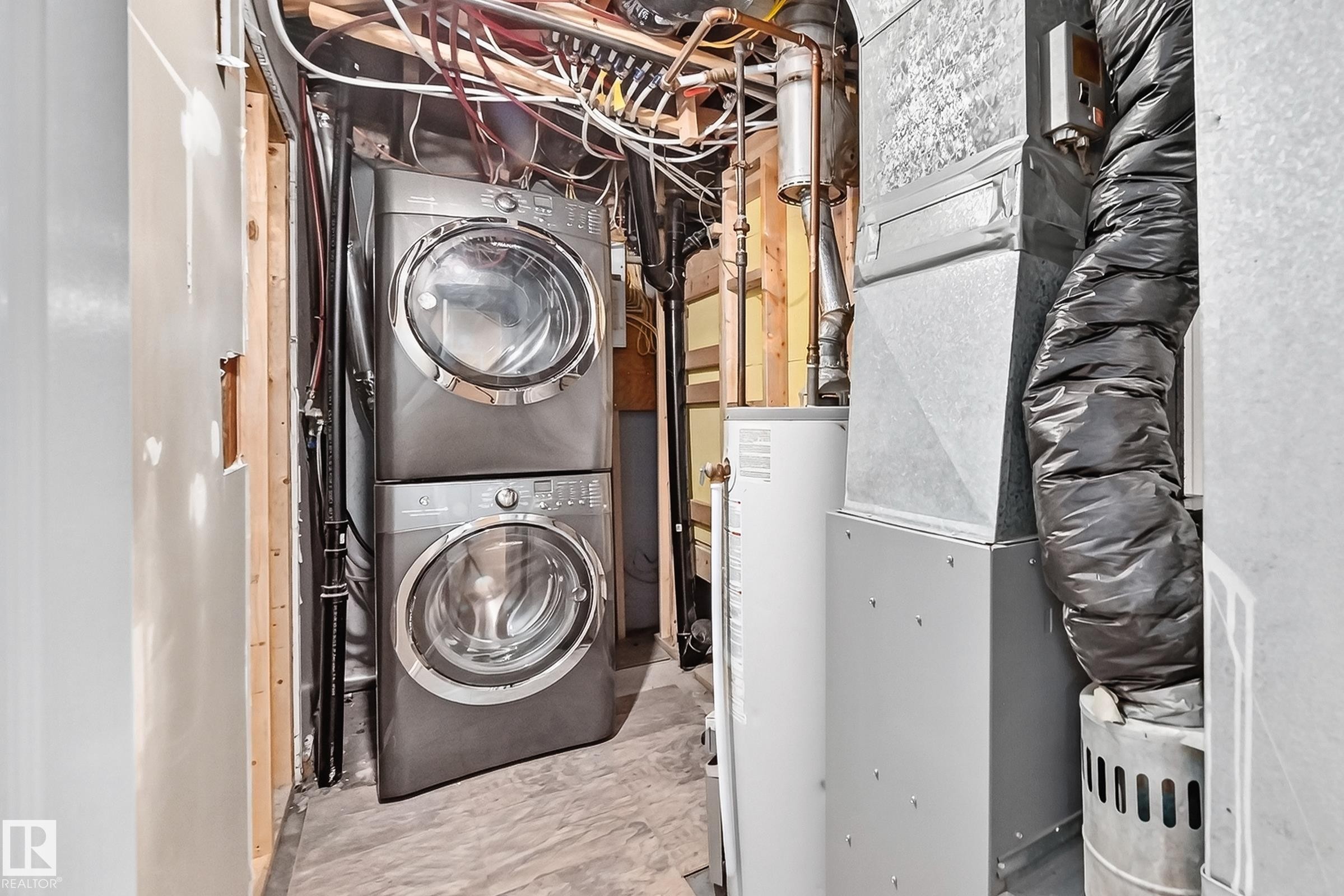Stackable washer and dryer, water heater, and ductwork - 50 Rocque, Fort Saskatchewan, AB - Indoor Photo Showing Laundry Room