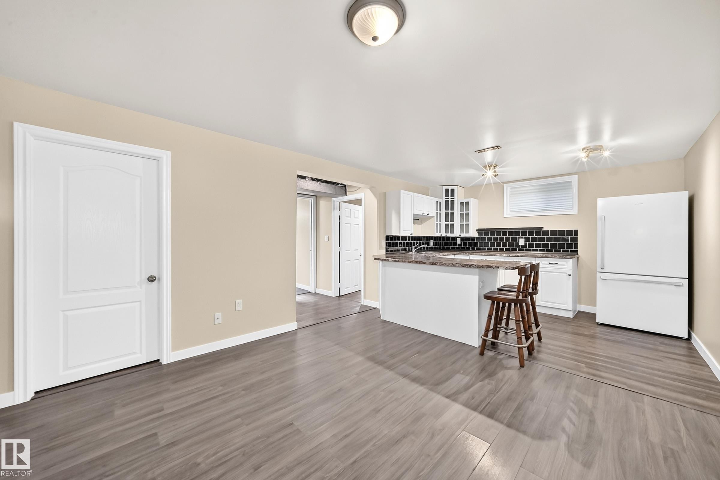 Kitchenette with white cabinetry, a peninsula island, and dark tile backsplash - 50 Rocque, Fort Saskatchewan, AB - Indoor Photo Showing Kitchen