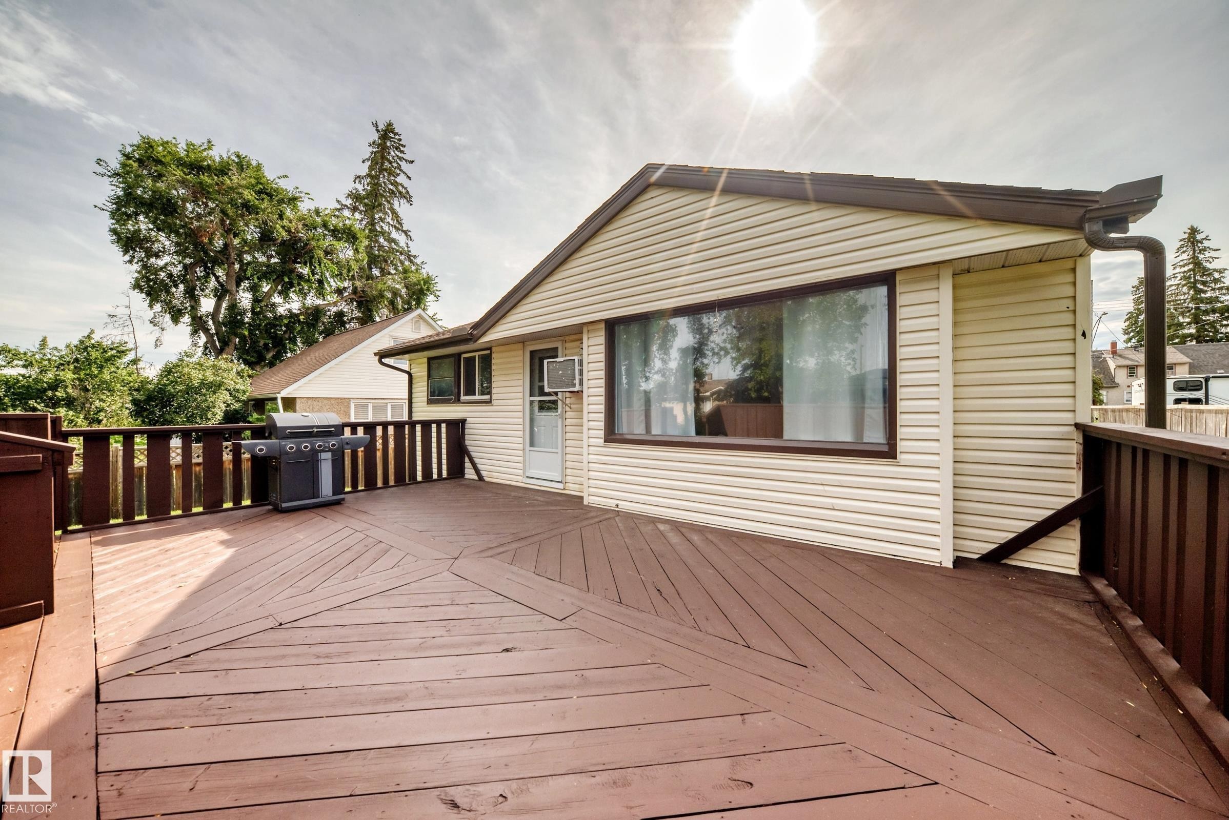 Expansive wood-finish deck with geometric plank pattern, perimeter railing, and direct exterior access - 50 Rocque, Fort Saskatchewan, AB - Outdoor With Exterior