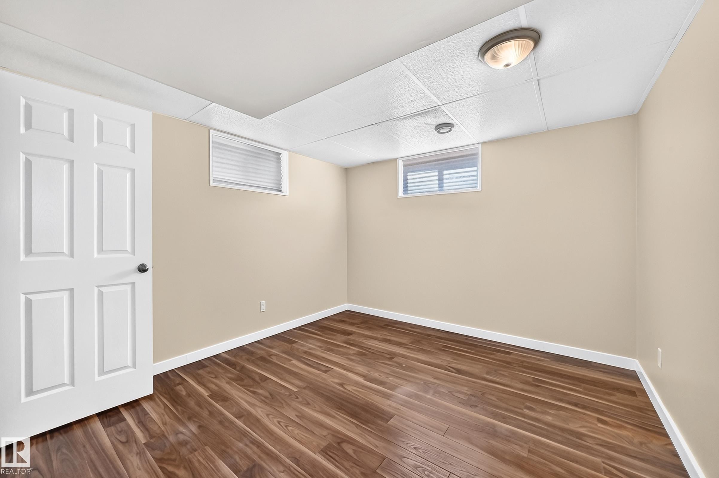 Finished basement room featuring warm beige walls, recessed ceiling lighting, and durable wood-finish flooring - 50 Rocque, Fort Saskatchewan, AB - Indoor Photo Showing Other Room