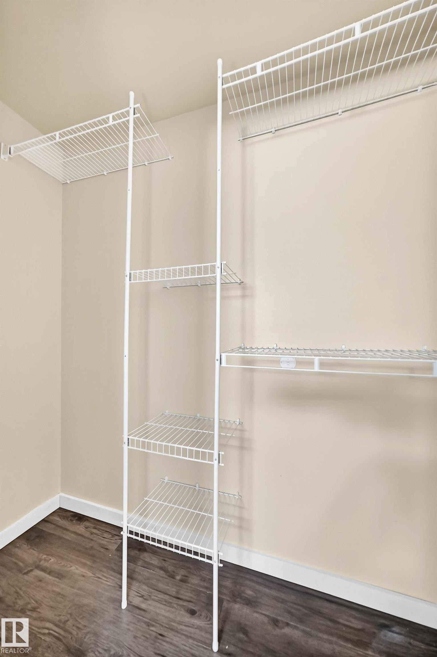 Wire shelving system with a hanging rod and wood-finish flooring - 50 Rocque, Fort Saskatchewan, AB - Indoor With Storage