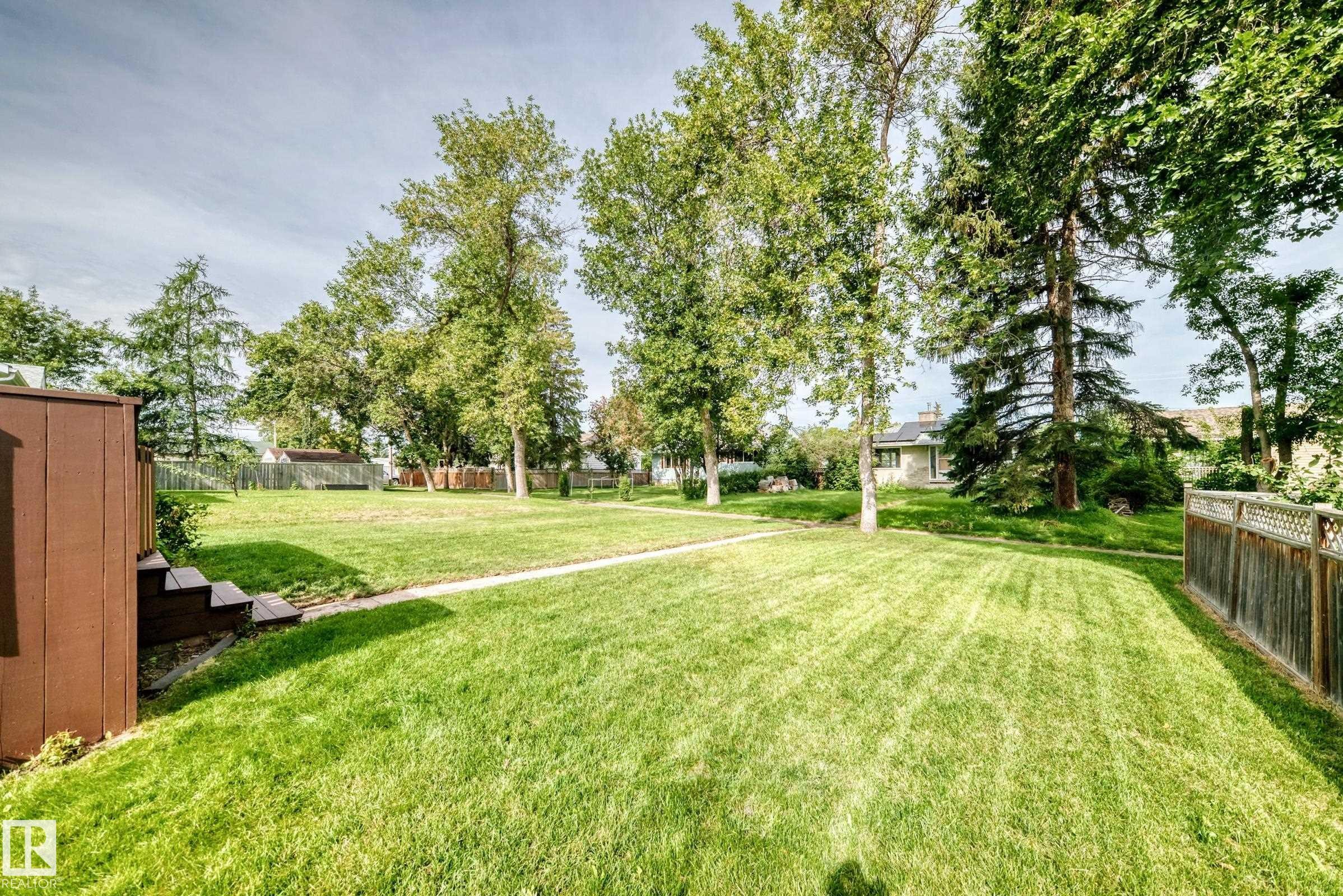 Expansive backyard featuring a lush lawn, mature trees, and a privacy fence - 50 Rocque, Fort Saskatchewan, AB - Outdoor