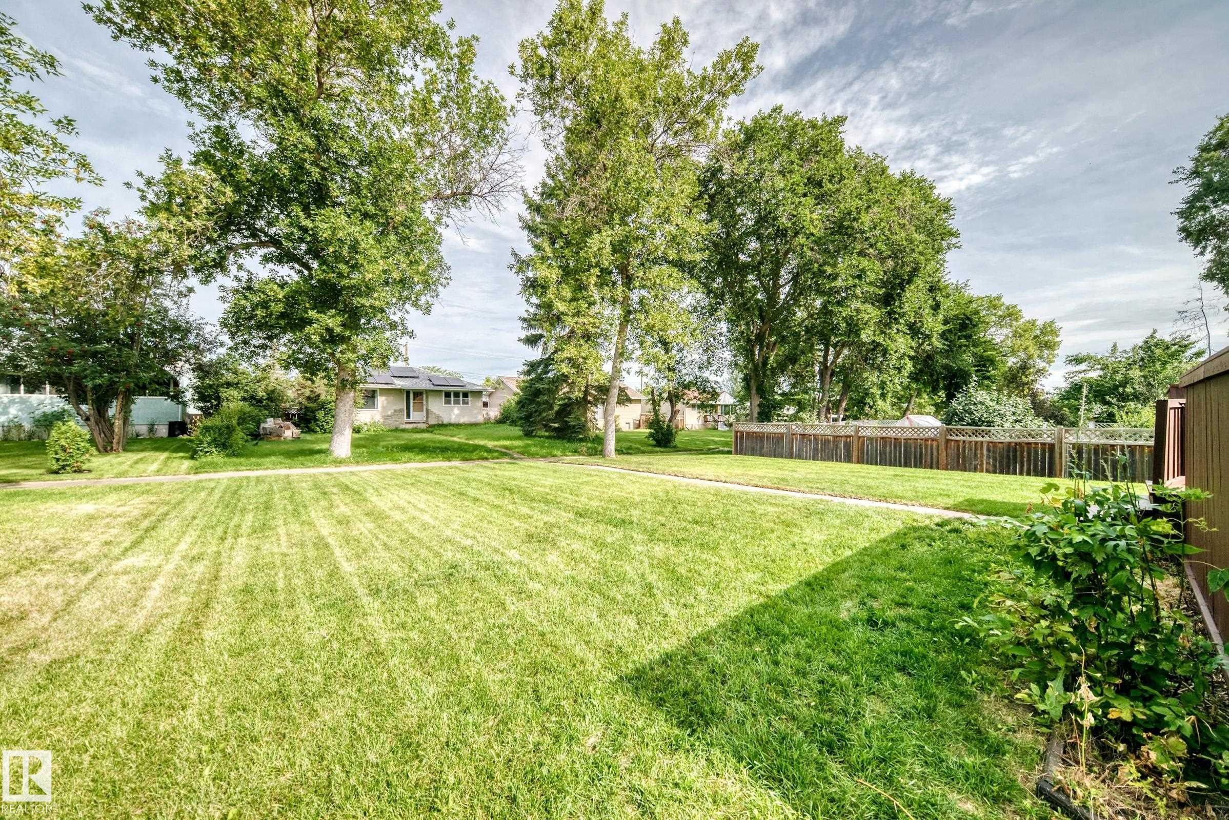 Expansive green lawn with mature trees and a wood privacy fence - 50 Rocque, Fort Saskatchewan, AB - Outdoor