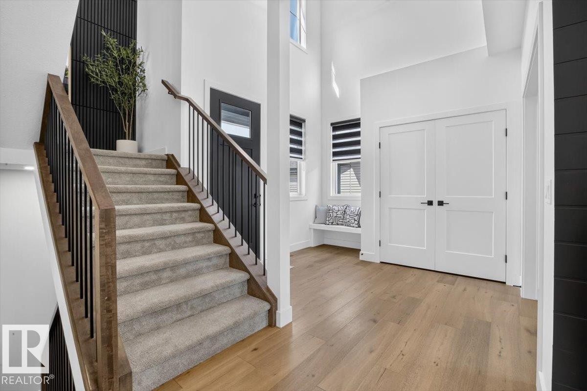 Carpeted staircase with wood-finish handrail and black metal balusters - 94 Harvest Crescent, Ardrossan, AB - Indoor Photo Showing Other Room